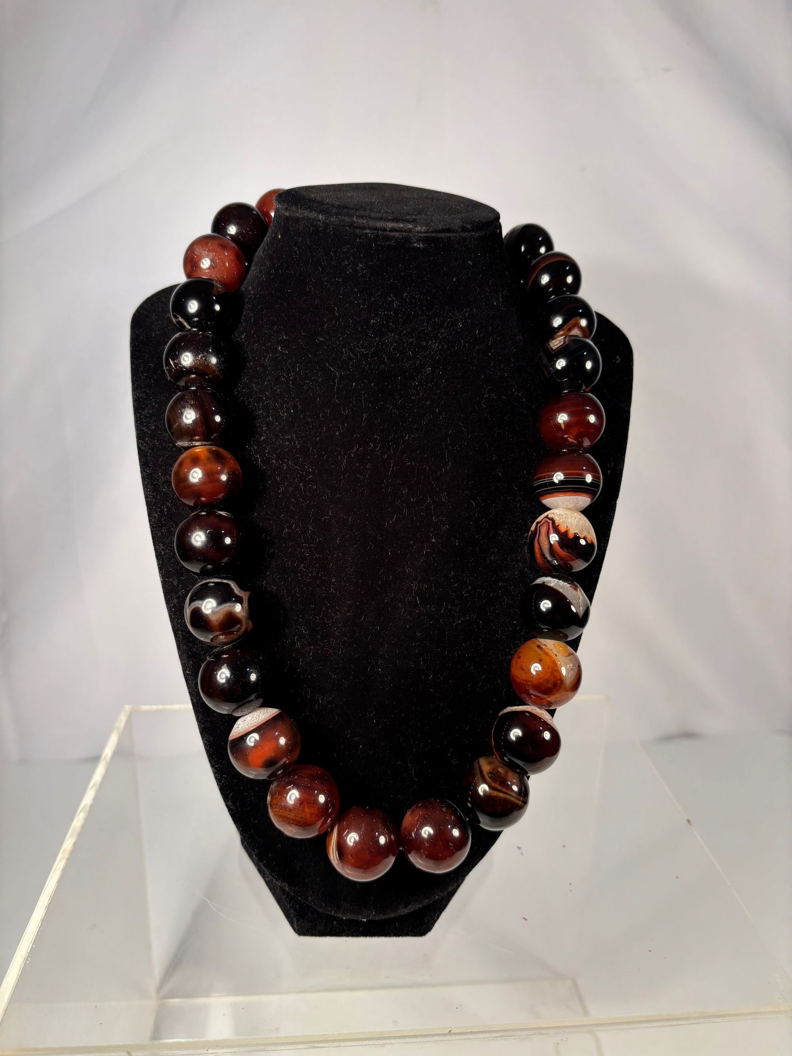Large Banded Agate Bead Necklace: A striking necklace composed of large natural banded agate beads, displaying dramatic contrasts of deep black, rich brown, and warm amber tones with natural eye and stripe patterns. Each bead is well-