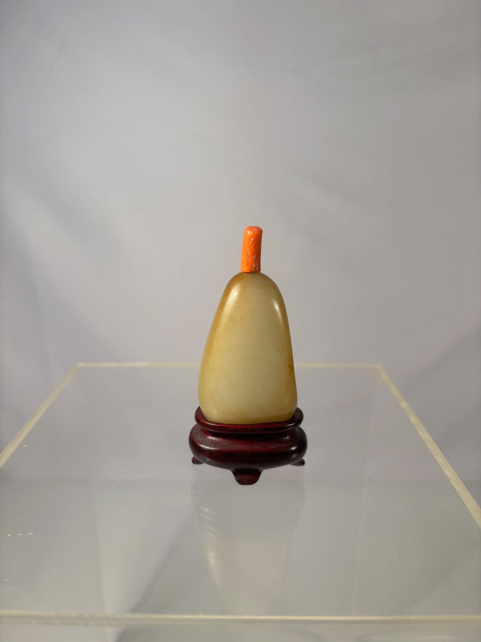 Chinese White Nephrite Jade Snuff Bottle with Natural Yellow Skin & Coral Stopper: Qing dynasty (1644-1912) ; A finely crafted Chinese snuff bottle made from high-quality white Hetian nephrite jade featuring a natural yellow skin .The bottle is smoothly polished in a rounded pebble