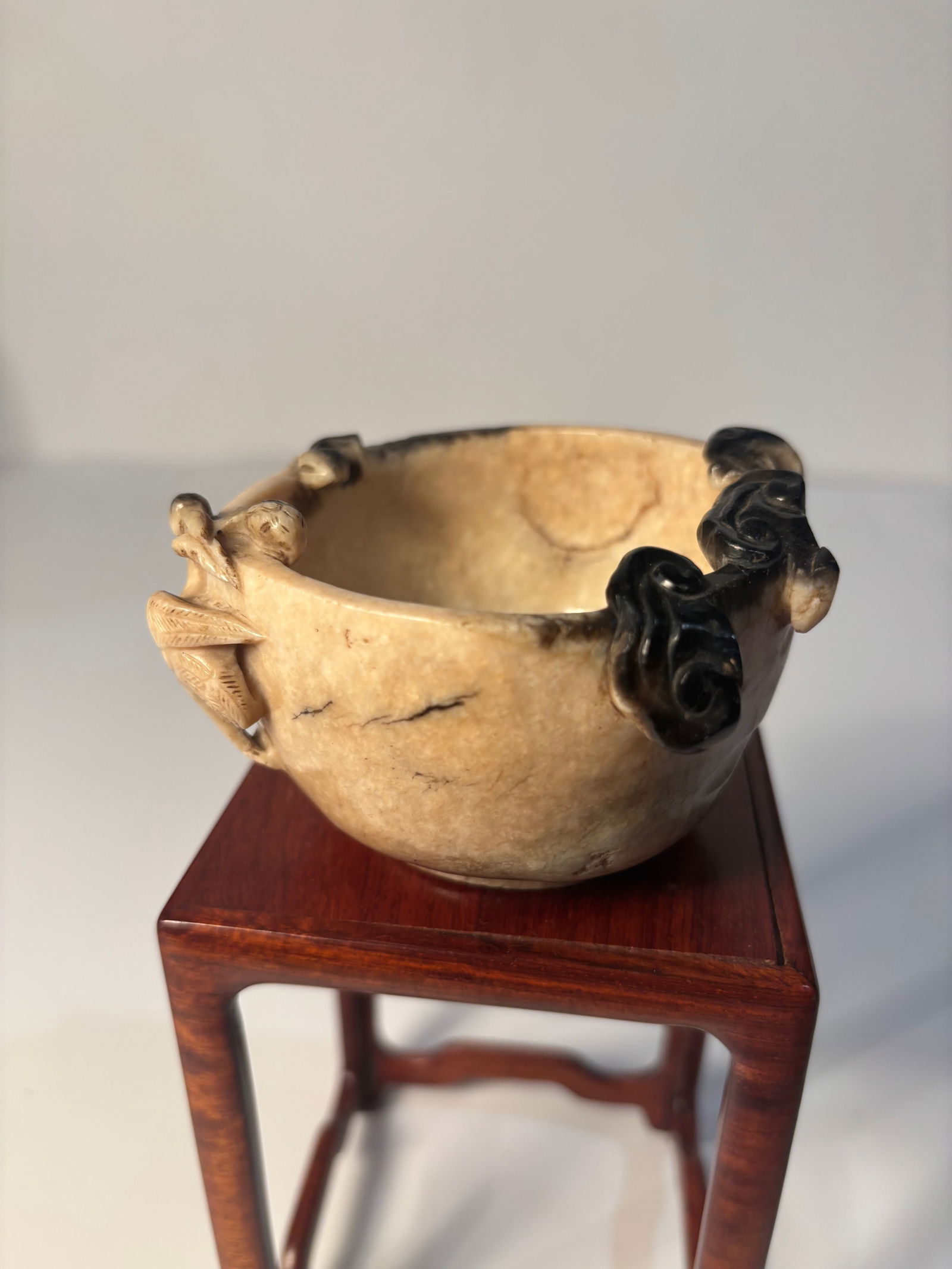 A Chinese hand carved nephrite Jade bowl with CRANES and RUYI: Ming Dynasty(1368-1644); The bowl is made from nephrite jade. The jade bowl is in a mottled or variegated color pattern that blends shades of creamy beige, light brown, and dark inclusions of black .