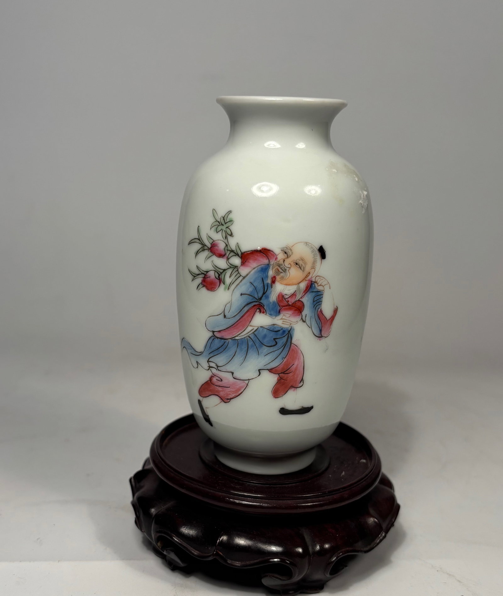 A Chinese Famille Rose Porcelain Vase With QianLong mark: Qing Dynasty(1644-1912); A finely enameled porcelain vase depicting a boy carrying a large branch of ripe pomegranates, symbolizing fertility and abundance. Rendered in the famille rose palette on a w