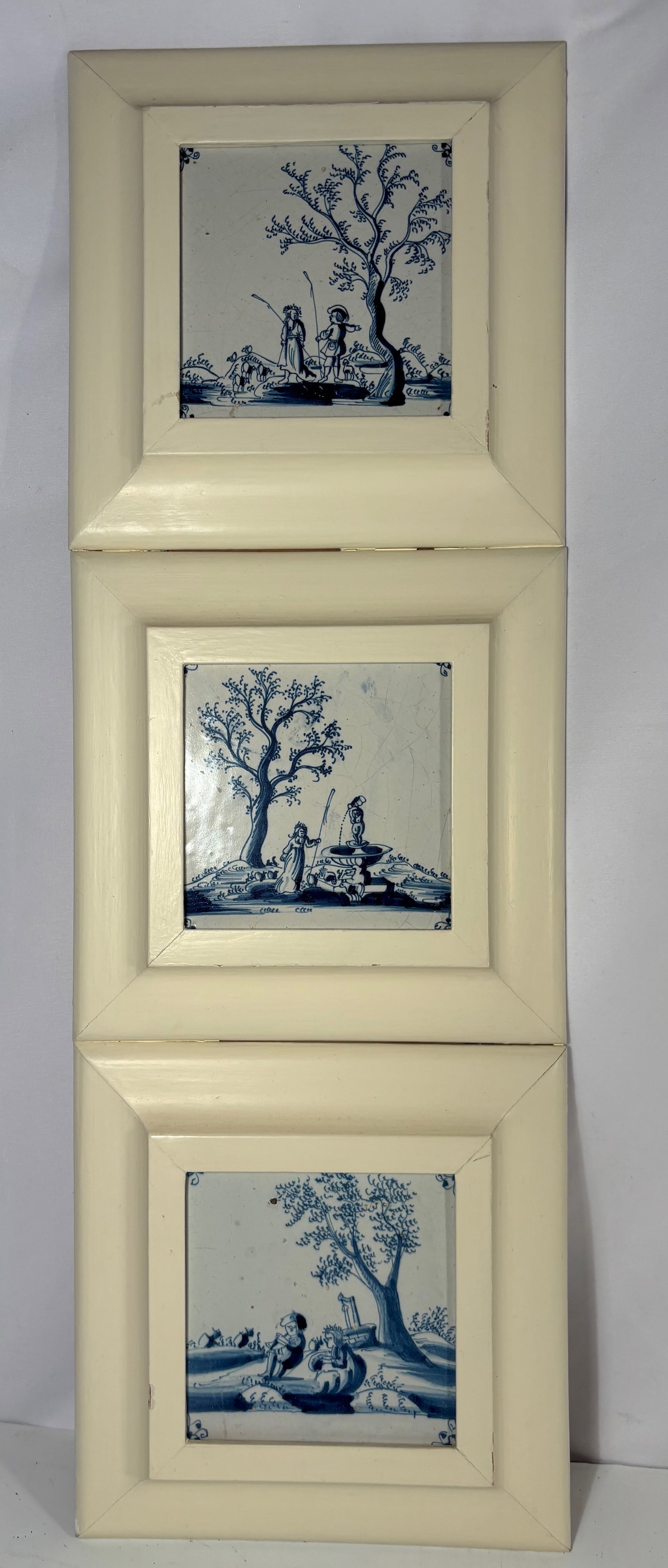 Set of Three Antique Dutch Delft Blue and White Tiles with Pastoral Scenes, 18th century: A set of three antique Dutch Delft blue and white ceramic tiles depicting pastoral scenes including figures fishing, shepherds, and a fountain. Each tile decorated with traditional corner motifs and p