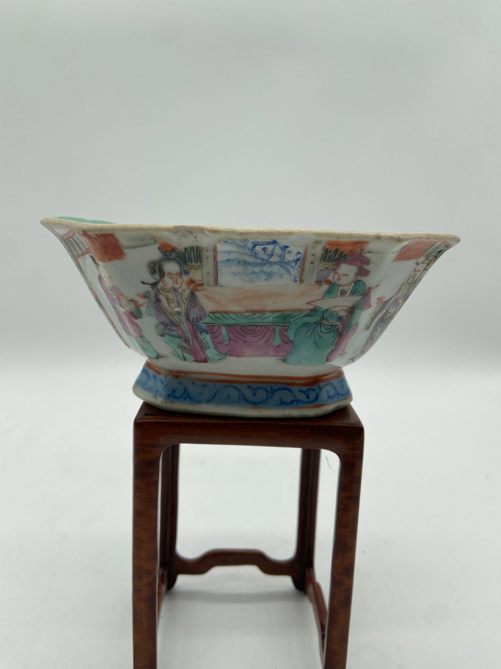 A Chinese famille rose porcelain cup with QIANLONG Four-Character mark in iron red: Qing dynasty (1644-1912); The cup depicts human figures, possibly immortals, musicians, or court attendants. Floral motifs and decorative patterns fill the surrounding space, enhancing the visual appe
