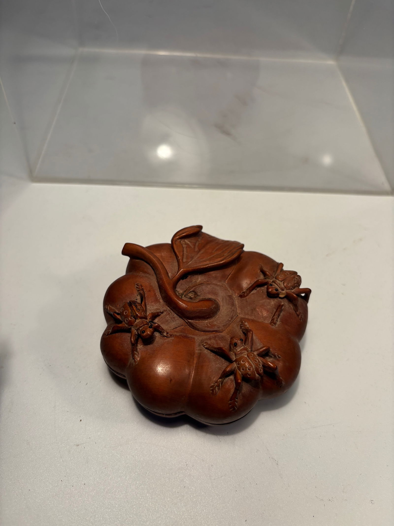 A Japanese Boxwood Case with Ink Stone, Signed Rissh? (??), Meiji–Taish? Period: A finely carved Japanese boxwood case (suzuribako) in the form of a ripe persimmon, the surface naturalistically modeled with curling leaves, tendrils, and insects in high relief. The warm honey-brown