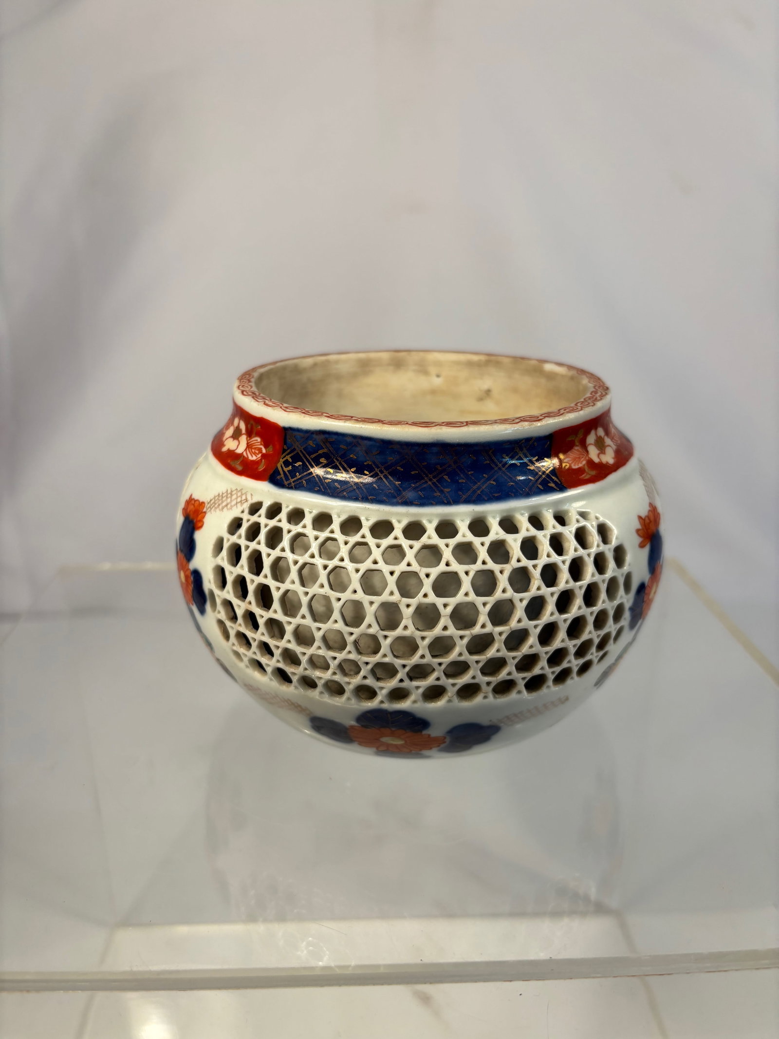A Japanese Reticulated Porcelain Incense Burner (K?ro), Meiji Period (1868–1912): Of compressed globular form with a short waisted neck and flat rim, the body delicately pierced with a lattice (reticulated) honeycomb design, overglazed with iron-red, cobalt blue, and gilt floral mo