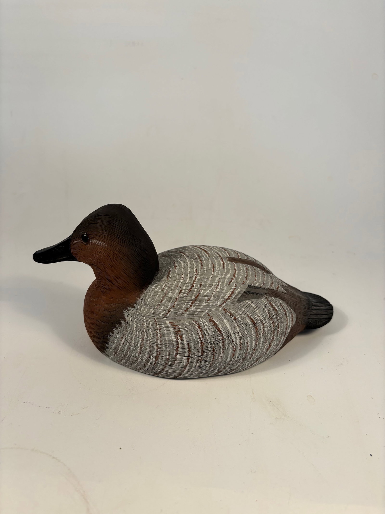 Hand-Carved Hen Decorative Carving signed and dated 1993: Hand-carved and painted wooden decoy of a Canvasback hen, featuring tight feather detail with soft gray, brown, and black tones. Signed and dated underneath.Part of the American Wildlife Collection by