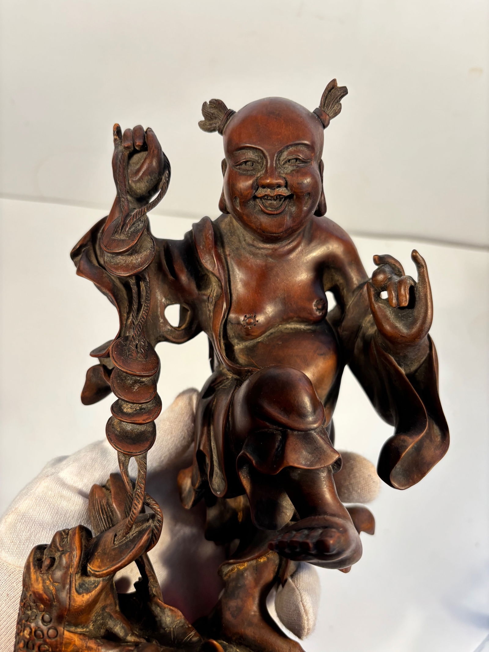 A Chinese hand carvd Child with a Three leg toad boxwood statue: Qing Dynasty (1644-1912), The joyful expression and hairstyle suggest the figure is a child deity or immortal.Dimensions? Height: 9.5 inches.
