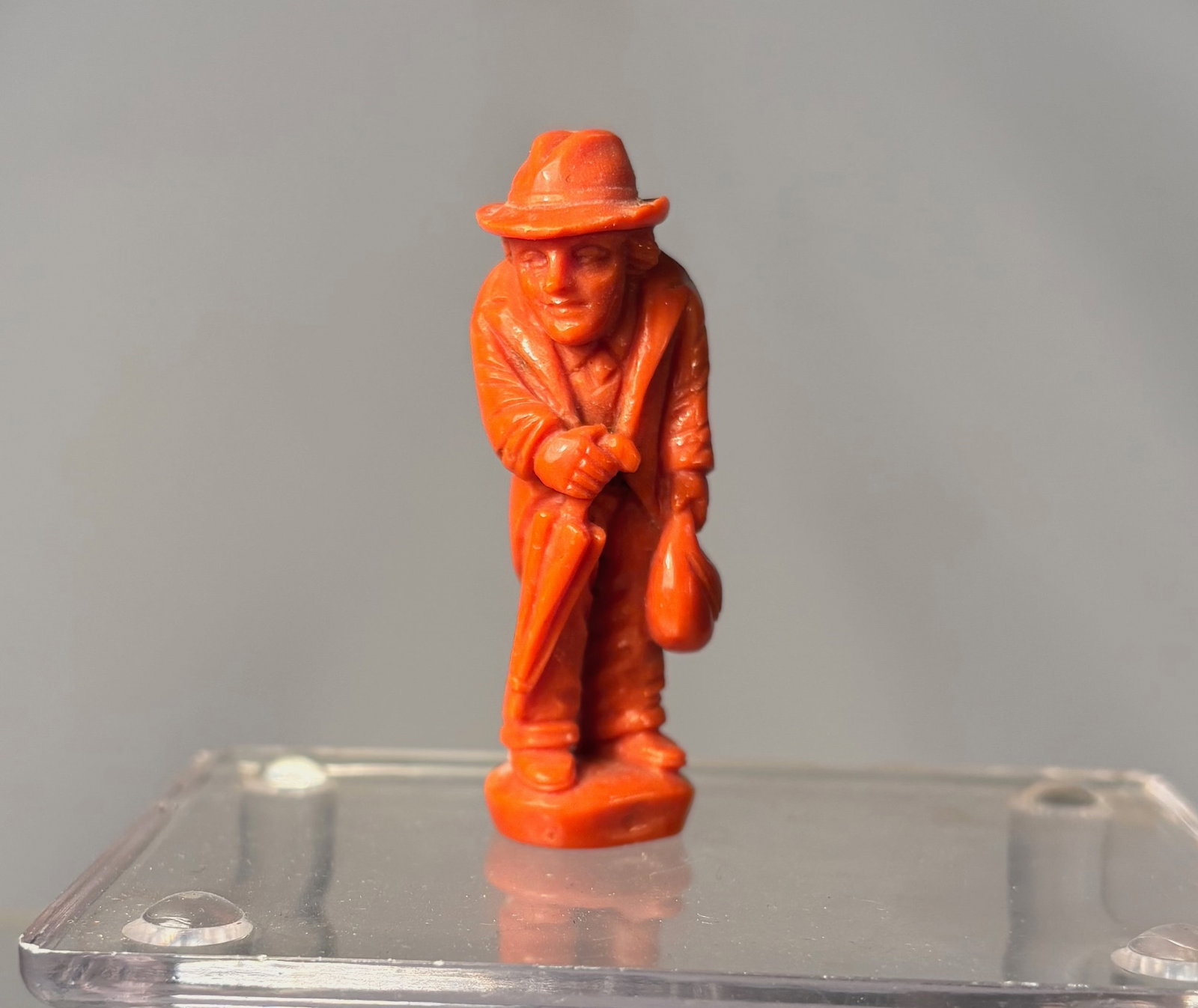 A Mediterranean Coral Carved Figure of a Gentleman: An antique carved figure executed in natural Mediterranean coral, depicting a standing gentleman wearing a hat and holding an umbrella. The figure is finely carved in the round, with well-defined faci