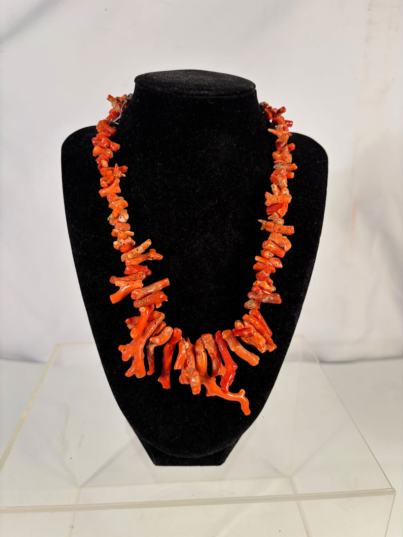 A Natural Mediterranean Red Coral Branch Necklace with Silver Clasp: Natural red coral branch necklace composed of irregular coral branch segments in vibrant orange-red tones. The branches are drilled and strung to form a graduated necklace, with larger coral branches
