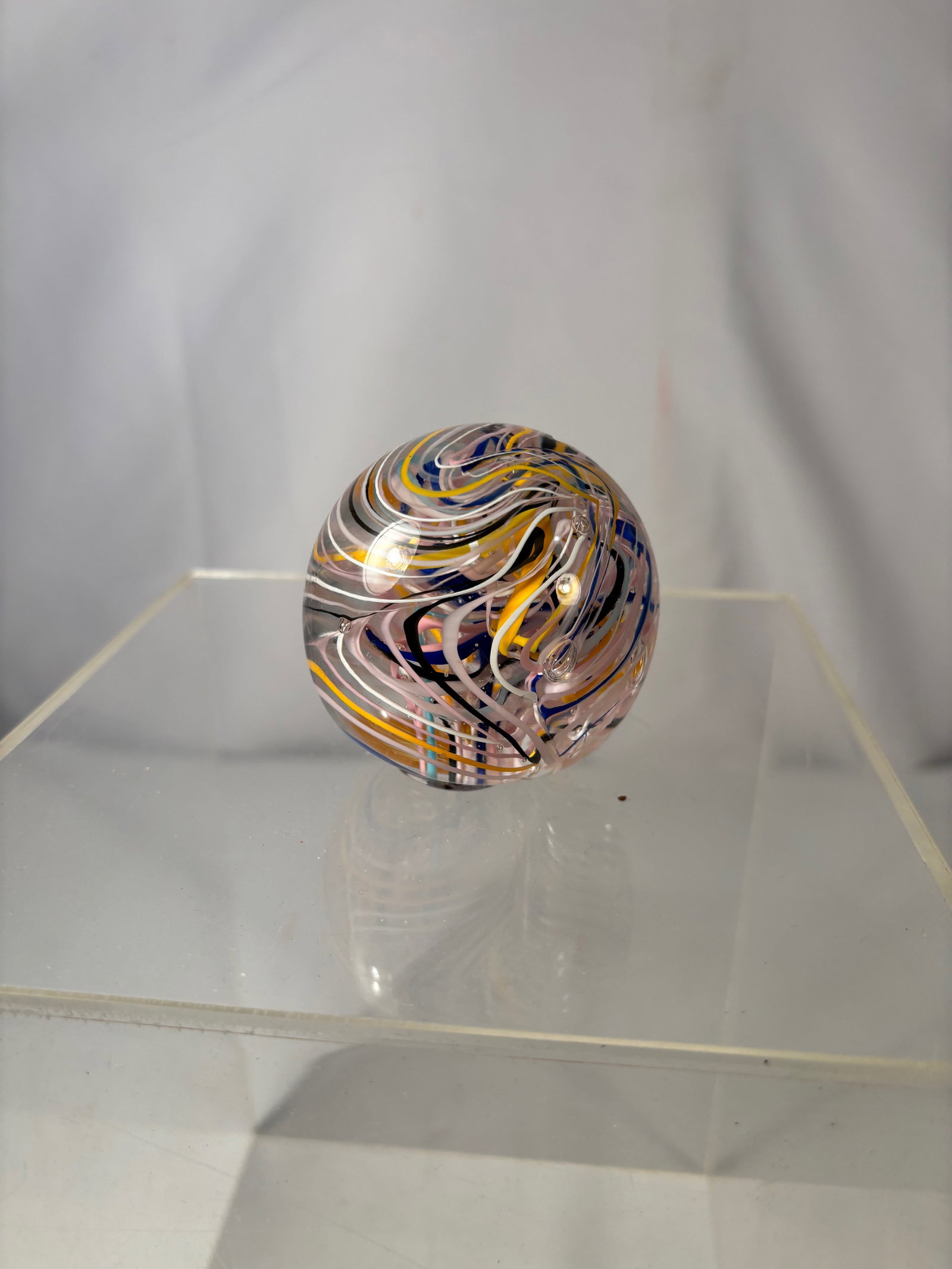 Italian Murano Style Art Glass Paperweight, Multicolor Spaghetti Swirl Design: This decorative art glass paperweight features a clear ground filled with dynamic multicolored ribbon-like trails in white, yellow, and blue. The layered strands create a sense of movement and depth,