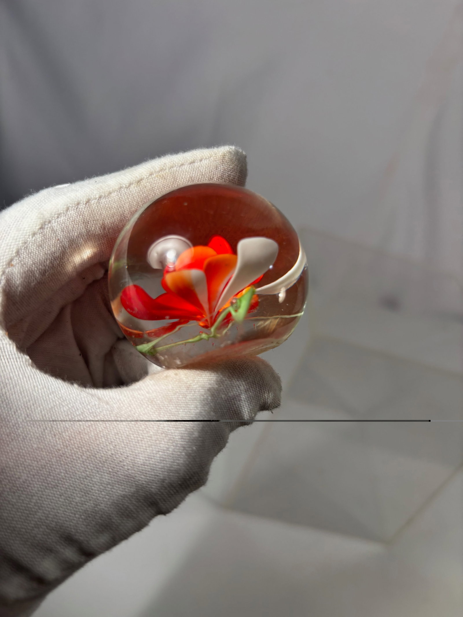 Studio Art Glass Paperweight w/ Red & Orange Floral Design: A hand-blown studio art glass paperweight featuring a stylized red and orange floral motif with layered petal forms and white accents, encased in a clear glass dome. The composition is well-centered w