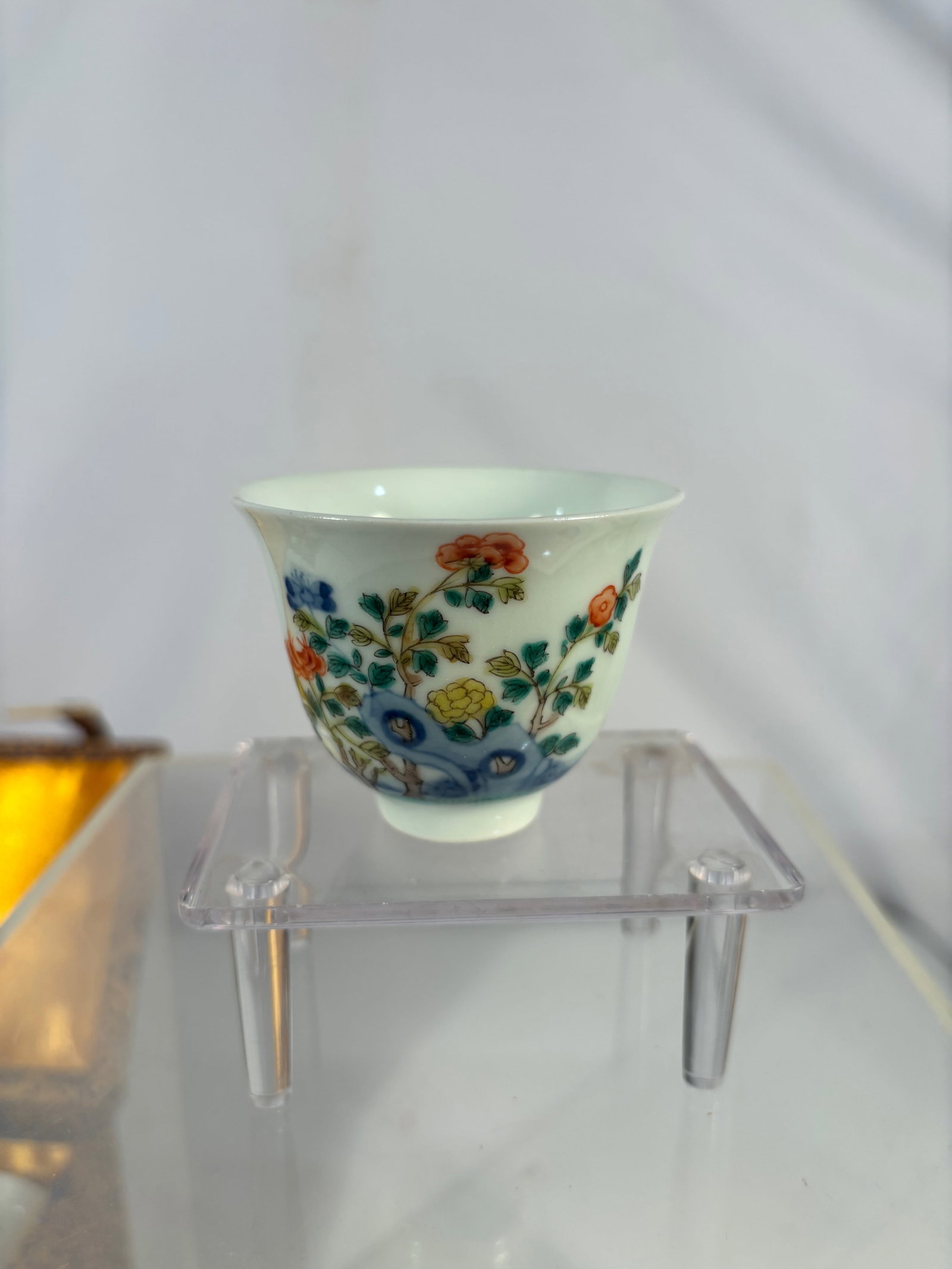 A Chinese Famille Rose Porcelain Cup, Kangxi Mark: 20th century; A Chinese porcelain cup decorated in famille rose enamels, finely painted with flowering branches in vibrant tones against a white ground. The exterior features delicate floral motifs, w