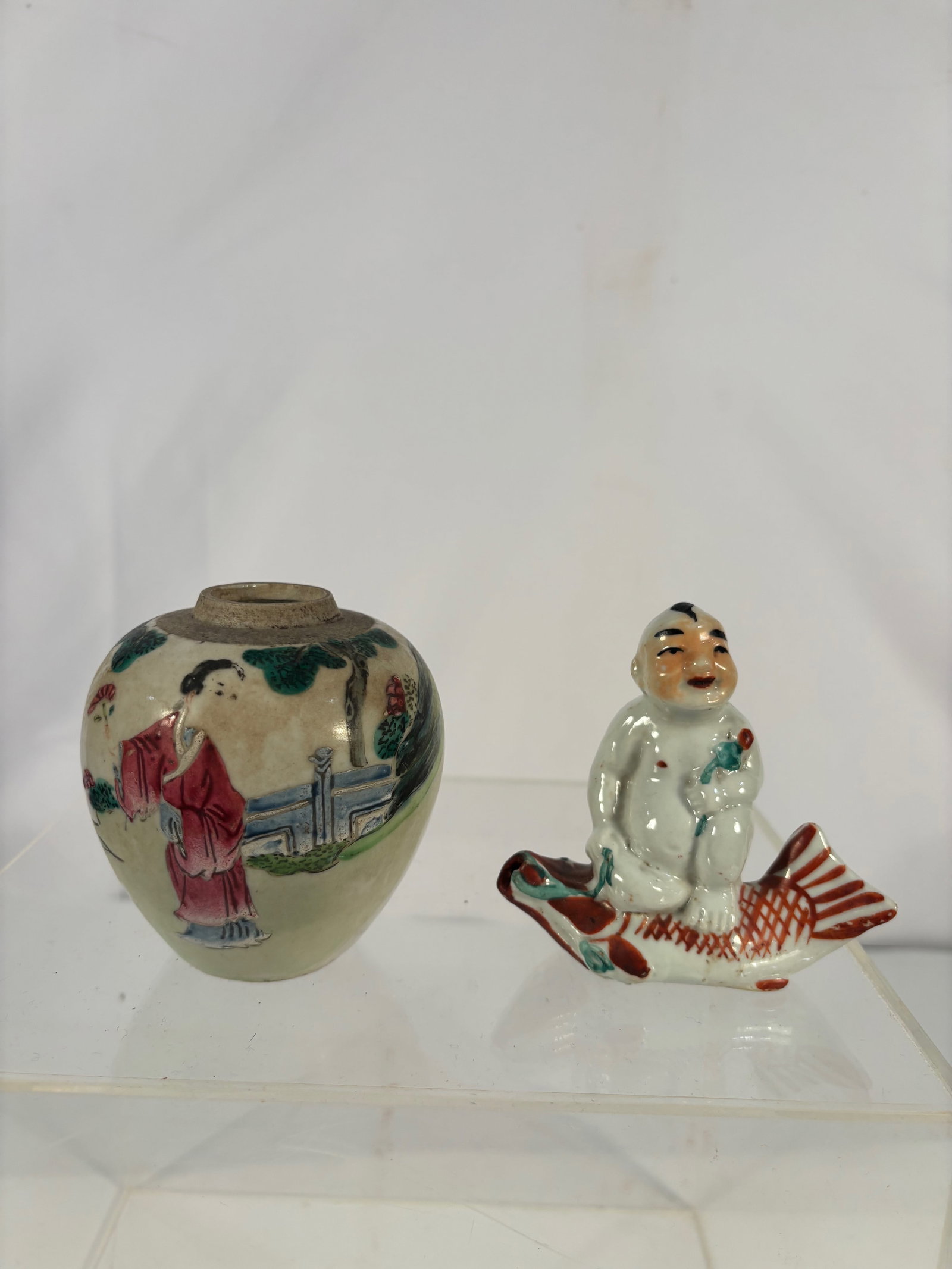 Two Chinese Qing Dynasty Porcelain Miniatures, Figure and Small Jar: 19th century ; A group of two Chinese porcelain miniatures, comprising a small painted jar decorated with figures in a garden setting, and a figural porcelain ornament depicting a seated figure riding