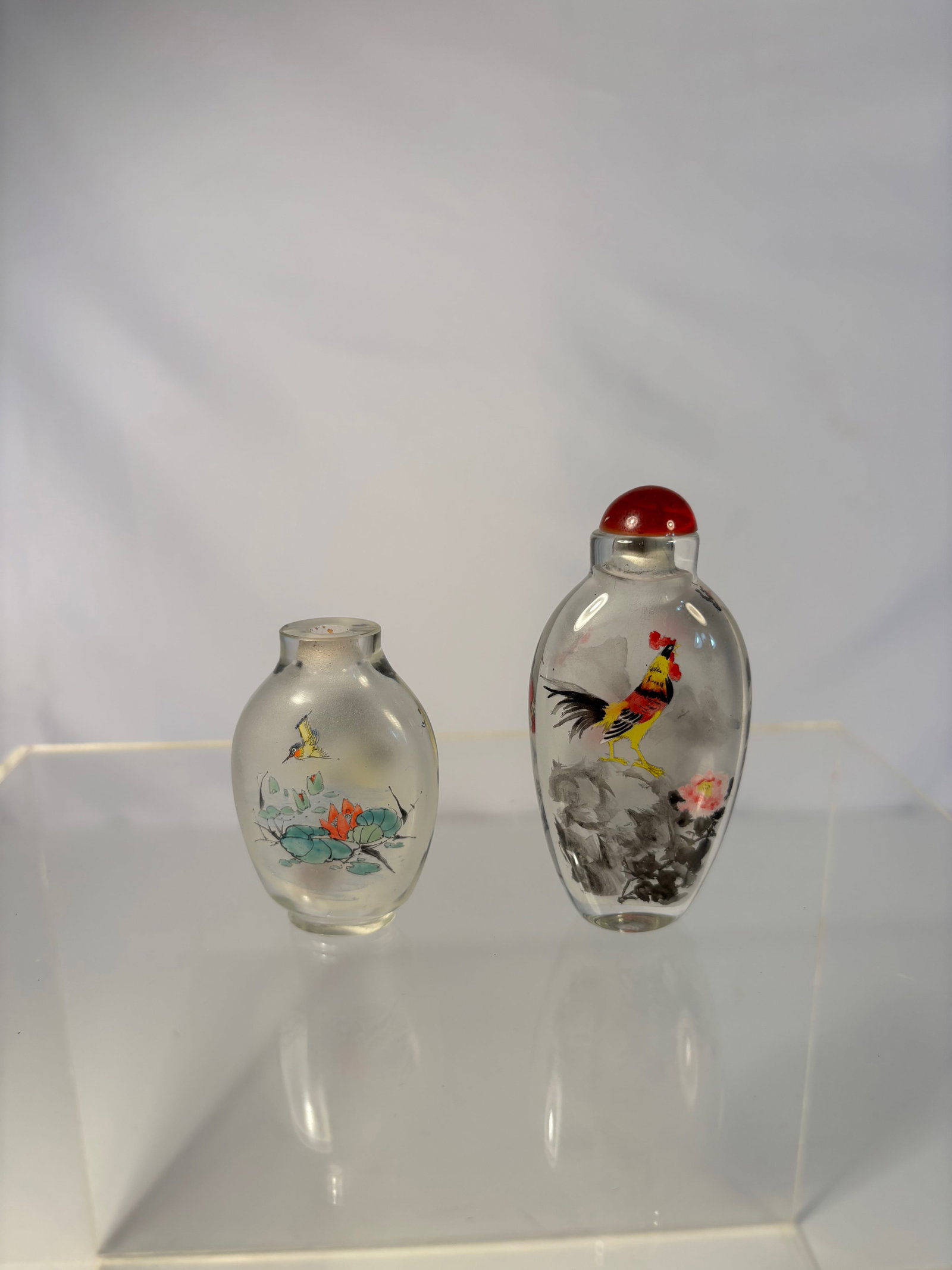 Two Chinese Inside-Painted Glass Snuff Bottles: Early 20th century ; Chinese inside-painted snuff bottles, each of flattened ovoid form, finely painted to the interior with colorful bird and flower scenes including roosters among peonies and a lotu