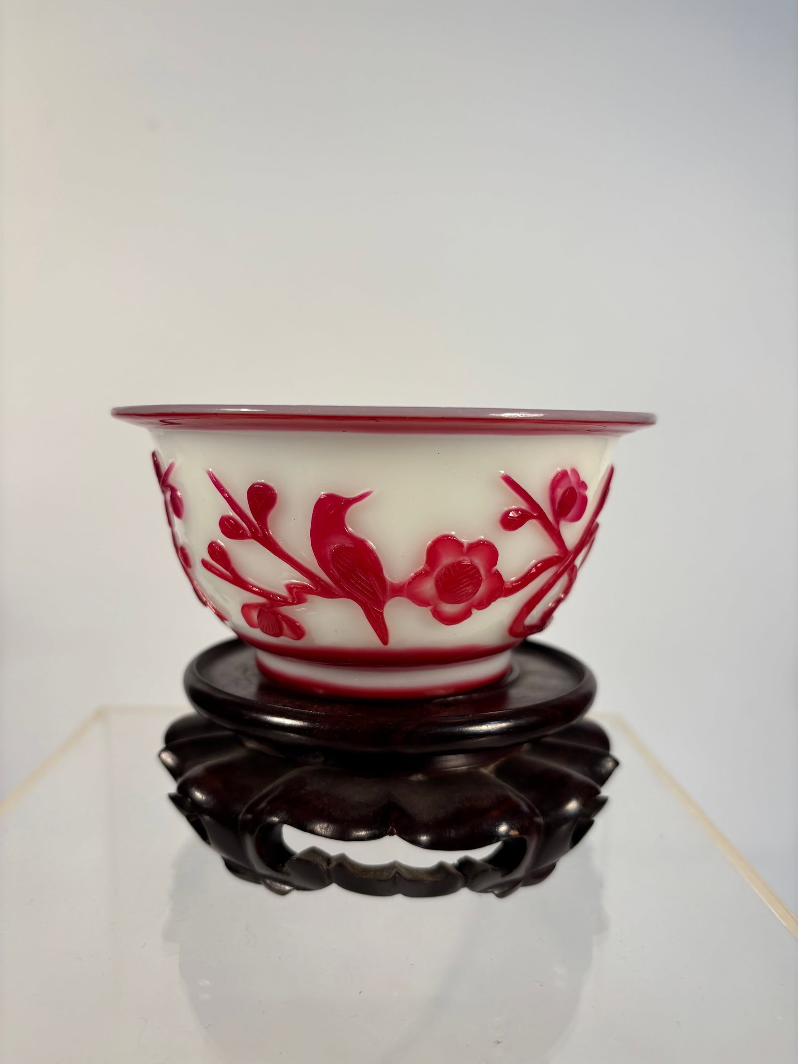 A Chinese Red Overlay Peking Glass Bowl carved "MADE IN CHINA": Qing Dynasty(1644-1912); A finely crafted Chinese red overlay Peking glass bowl, beautifully carved with a vivid birds and blossoming branches motif. The vessel is composed of opaque white glass overl