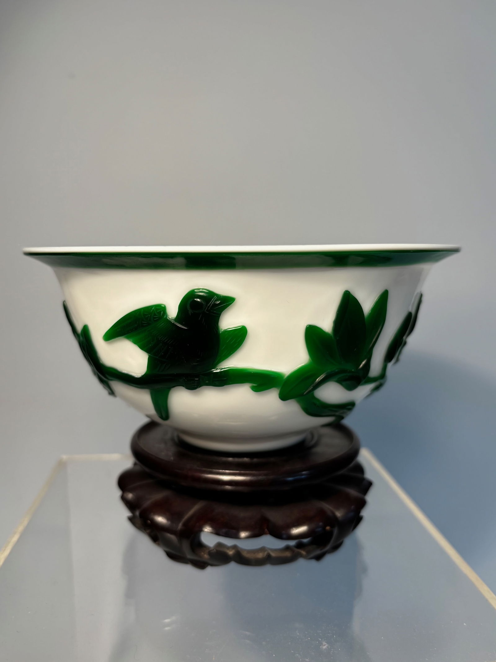 A Chinese Peking Overlay Glass Bowl with Green Lotus Design on White Ground: Qing Dynasty(1644-1912); A finely crafted Chinese Peking overlay glass bowl, featuring a vibrant emerald green overlay carved in relief to depict blossoming lotus flowers and foliage on an opaque whit