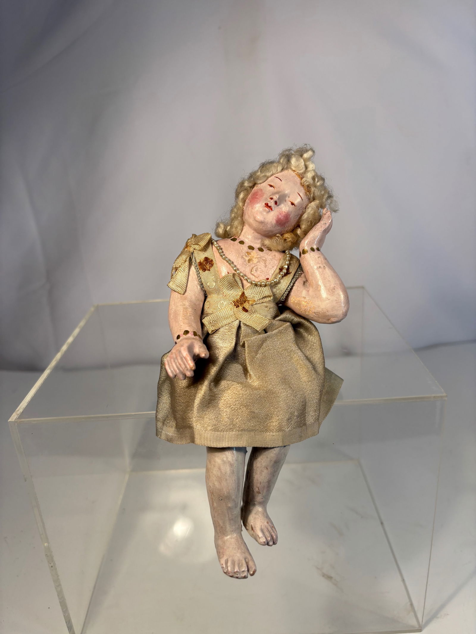 Neapolitan Polychrome Terracotta and Gesso Figure of a Seated Girl, 18th Century: Finely modeled figure depicting a young kid in a contemplative pose, with delicately painted features, a applied wool hair arranged in curls. Dressed in a period silk gown with ribbon and bead decorat