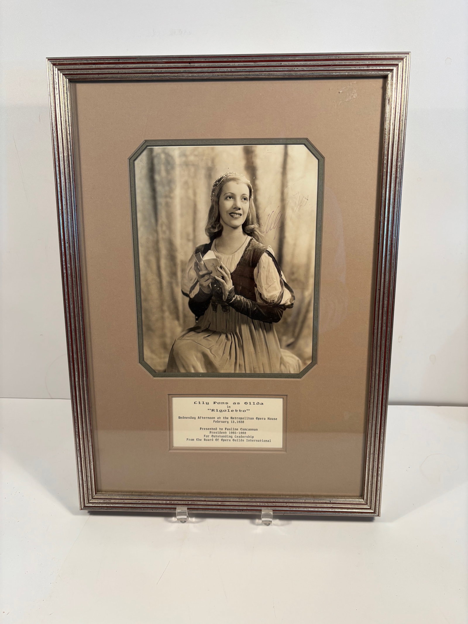 Framed photograph of Lily Pons with signature, the famous French-American operatic soprano.: It appears the photograph is signed by Lily Pons ; Subject: Lily Pons as Gilda in Rigoletto; Date/Location: February 13, 1938, at the Metropolitan Opera House ;Presented to: Pauline Cuncannan (noted a