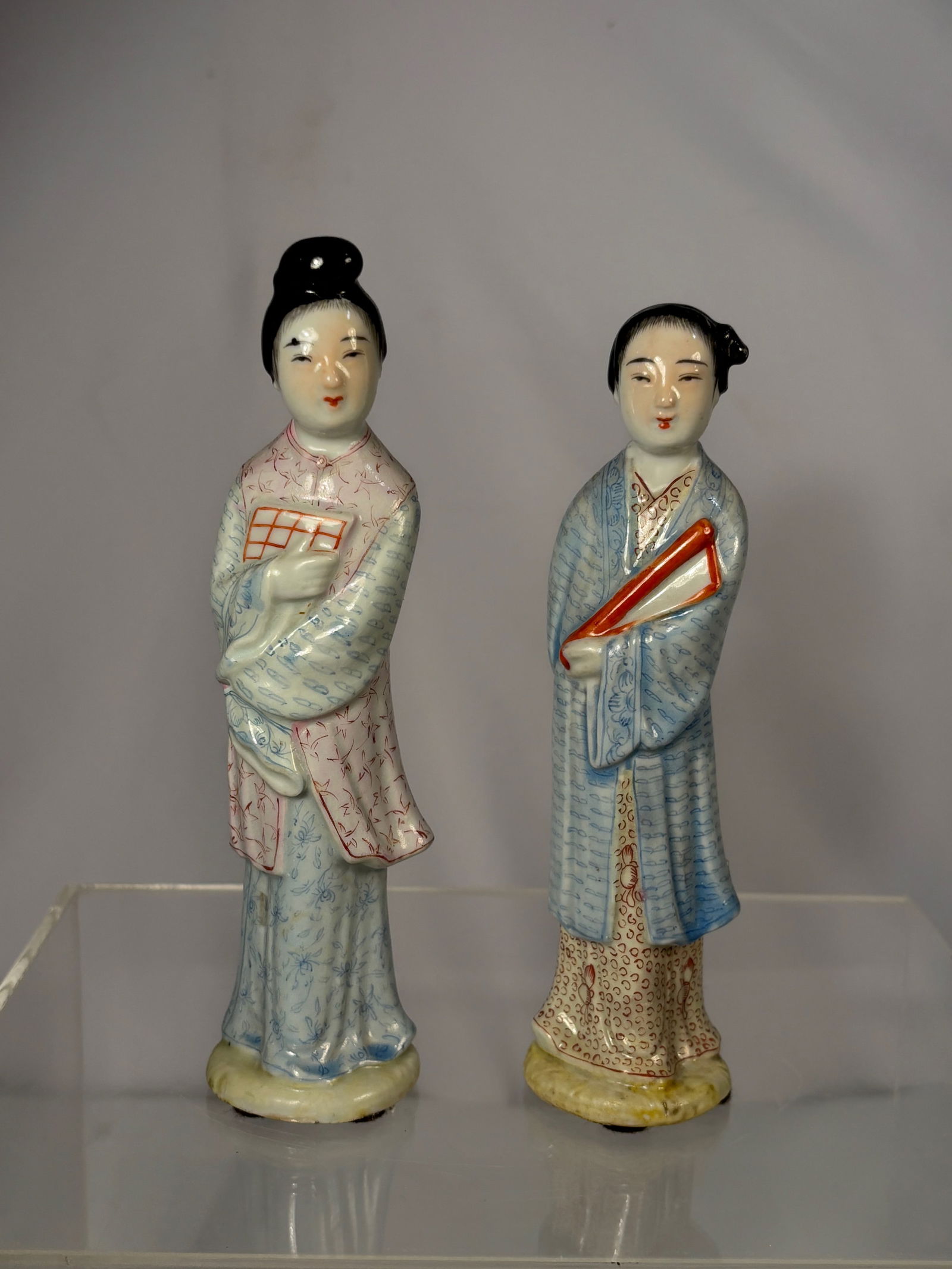 Pair of Chinese Porcelain Lady Figurines: Qing dynasty(1644-1912) ; A pair of Chinese porcelain figurines depicting standing ladies in traditional dress, hand-painted in soft pastel tones. Each figure is finished with a smooth glaze and stand
