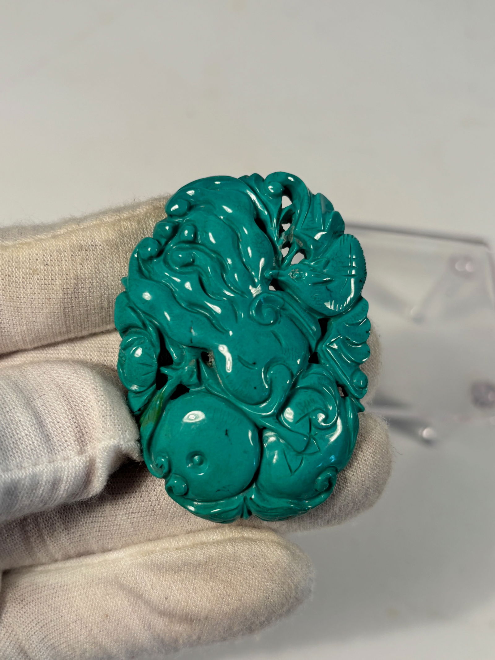 A Chinese Carved Turquoise Pendant of Gourds and Tendrils: Qing Dynasty (1644-1912); A Chinese turquoise carving, finely worked as a pendant depicting intertwined gourds, leafy vines, and curling tendrils—a traditional symbol of fertility and continuity. Di