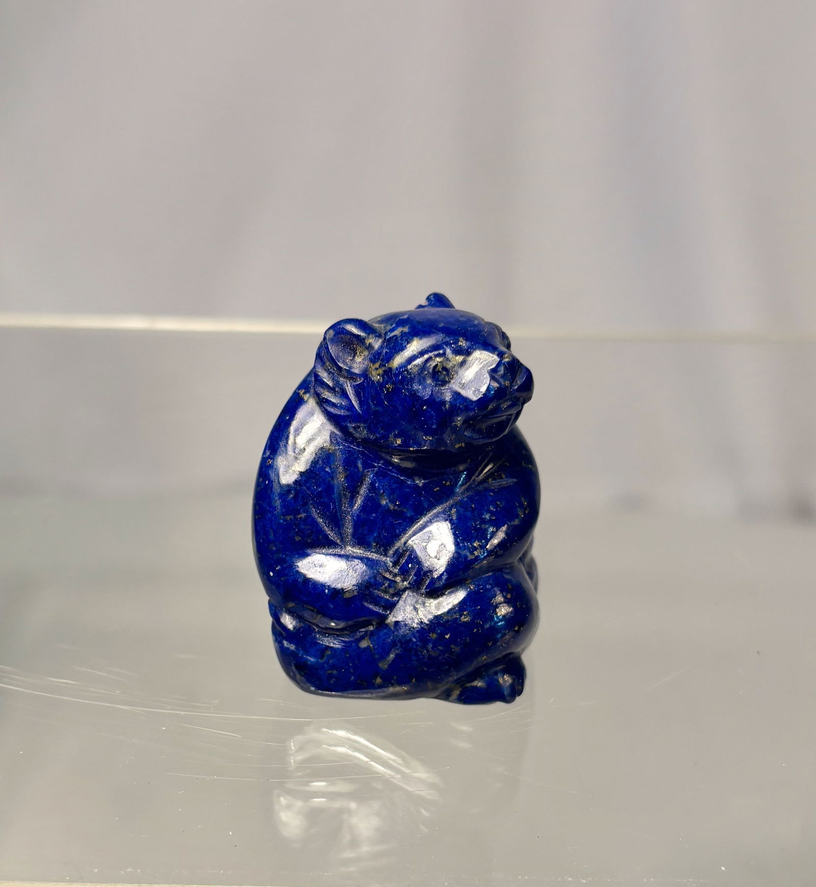 A Chinese Lapis-Lazuli Blue Glass Carving of a Bear: Qing dyansty(1644-1912) ; A finely shaped as a seated bear holding a small ball. The figure displays a rich deep-blue color reminiscent of natural lapis, with bright highlights and smooth polished sur
