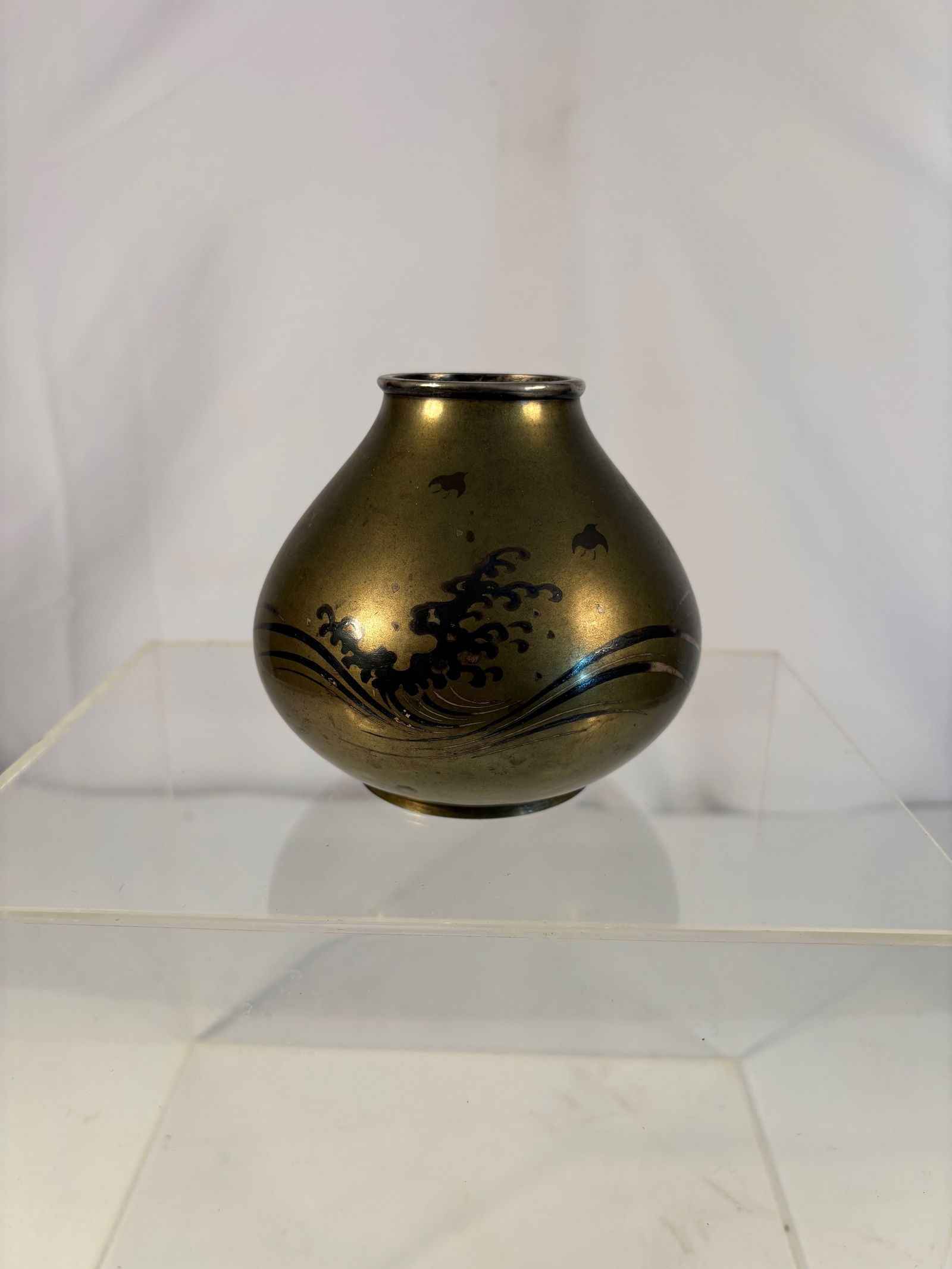 Japanese Bronze Vase with Silver Inlay and Silver-Mounted Rim Signed: Of rounded ovoid form with short neck and silver-mounted rim, the bronze body decorated in delicate silver z?gan (inlay) with stylized waves and spray motifs. The surface finished in a warm golden pat