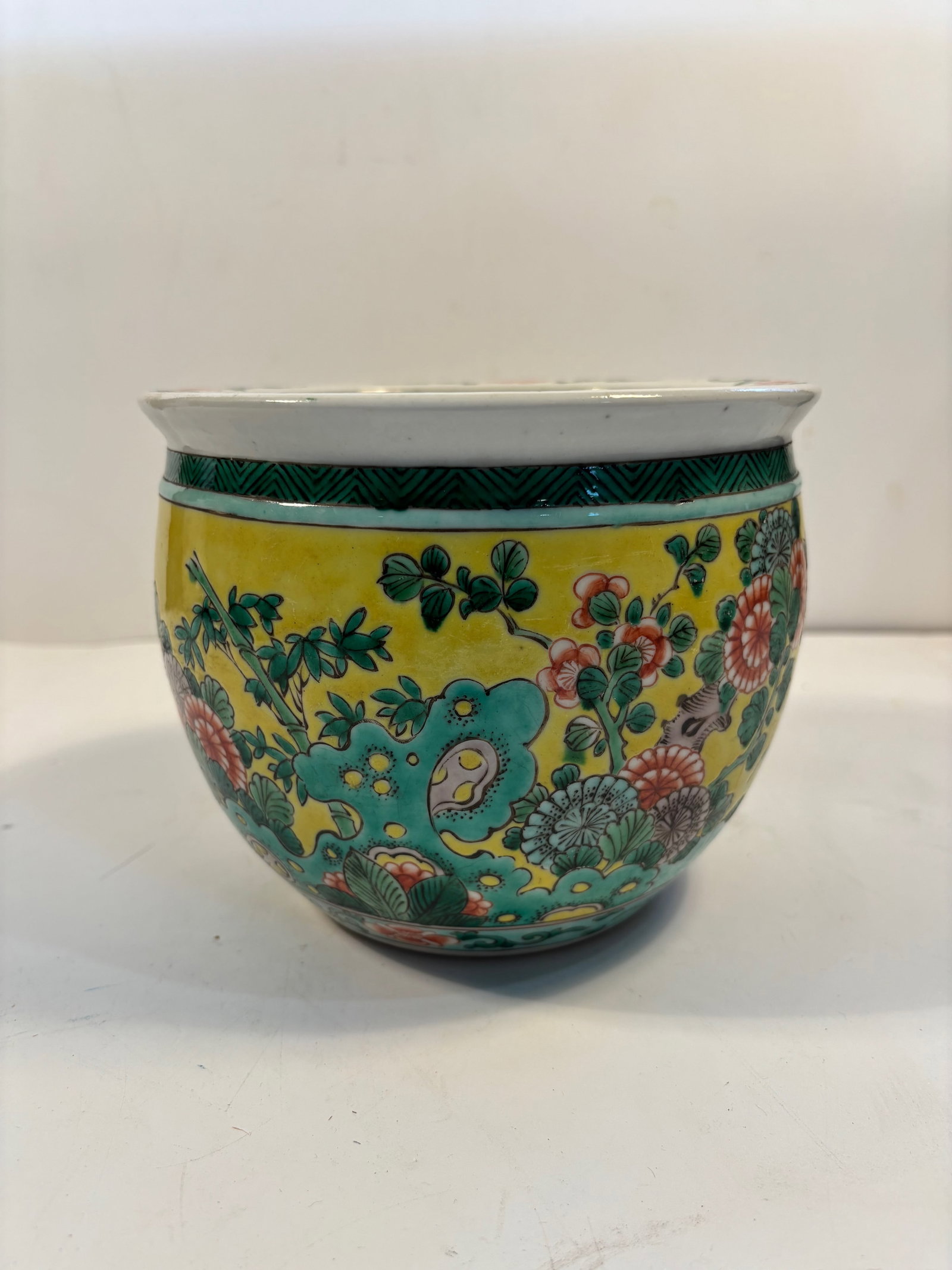 A Chinese Famille Verte porcelain jardinière: Qing Dynasty (1644-1912);Rich enamels in green, yellow, red, and turquoise depicting flowers and rocks ; Dimensions?Height: 6 INCHES ; Diameter: 6.25 INCHES.