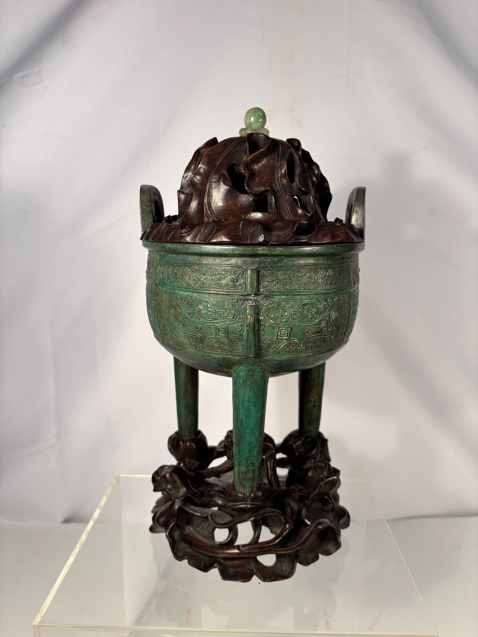 AN ARCHAISTIC BRONZE RITUAL TRIPOD VESSEL, DING: Qing Dynasty or early , Chinese bronze tripod censer, ding-form, featuring two upright loop handles and three tapered legs. The body is cast with decorative bands in a geometric archaistic motif. The