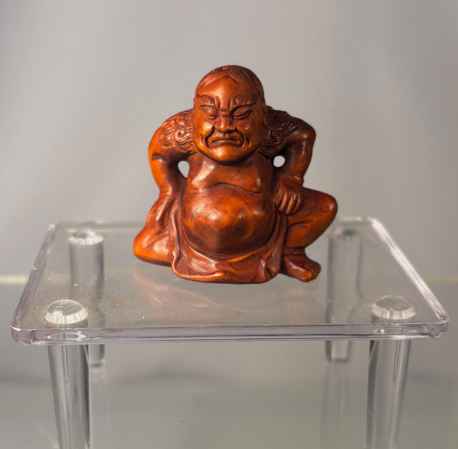 A Japanese Boxwood Netsuke of Daruma (Bodhidharma), Signed Gyokuseki: Meiji period (19th century),Carved Japanese netsuke in boxwood depicting Daruma (Bodhidharma) seated in a compact, rounded pose, his robe tightly wrapped around the body. The figure is rendered with a