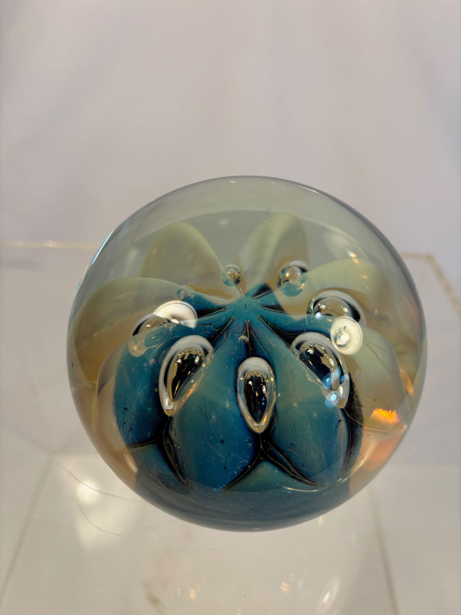 Signed Steven Eickholt Studio Art Glass Paperweight, 1998, Blue Swirl Design (WMSU): Handcrafted studio art glass paperweight by Steven Eickholt, dated 1998, inscribed on base “Eickholt 1988 WMSU.” The clear glass sphere encases swirling blue and iridescent inclusions with con