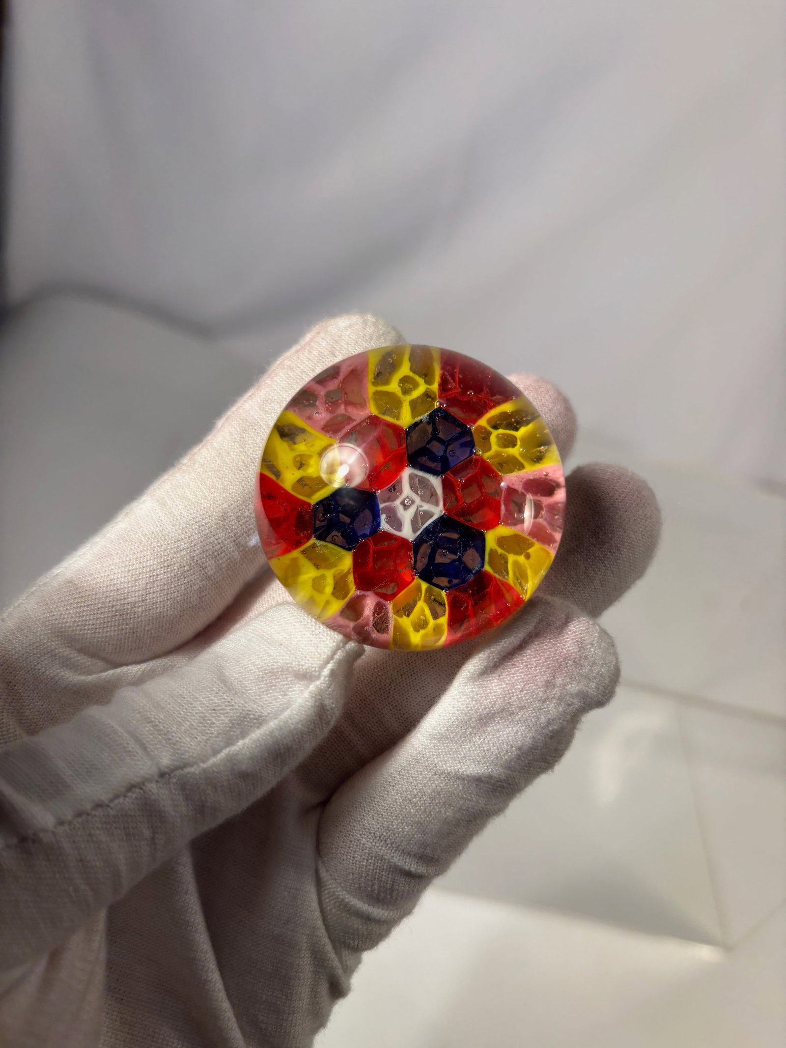 Art Glass Paperweight with Multicolor Interior Design: Decorative art glass paperweight featuring a clear domed body encasing a vibrant multicolor interior design in red, yellow, blue, and pink tones. The interior displays abstract color blocks and centra