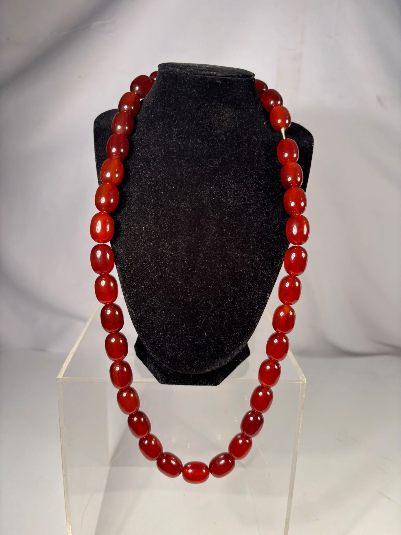 A Vintage Cherry Amber Bakelite Necklace, 33 Large Barrel Beads, 28 Inches, 123 grams: Vintage necklace composed of thirty-three uniform cherry amber Bakelite barrel beads, each approximately 20.2 mm in length. The beads display a translucent cherry-red glow under strong light. Overall
