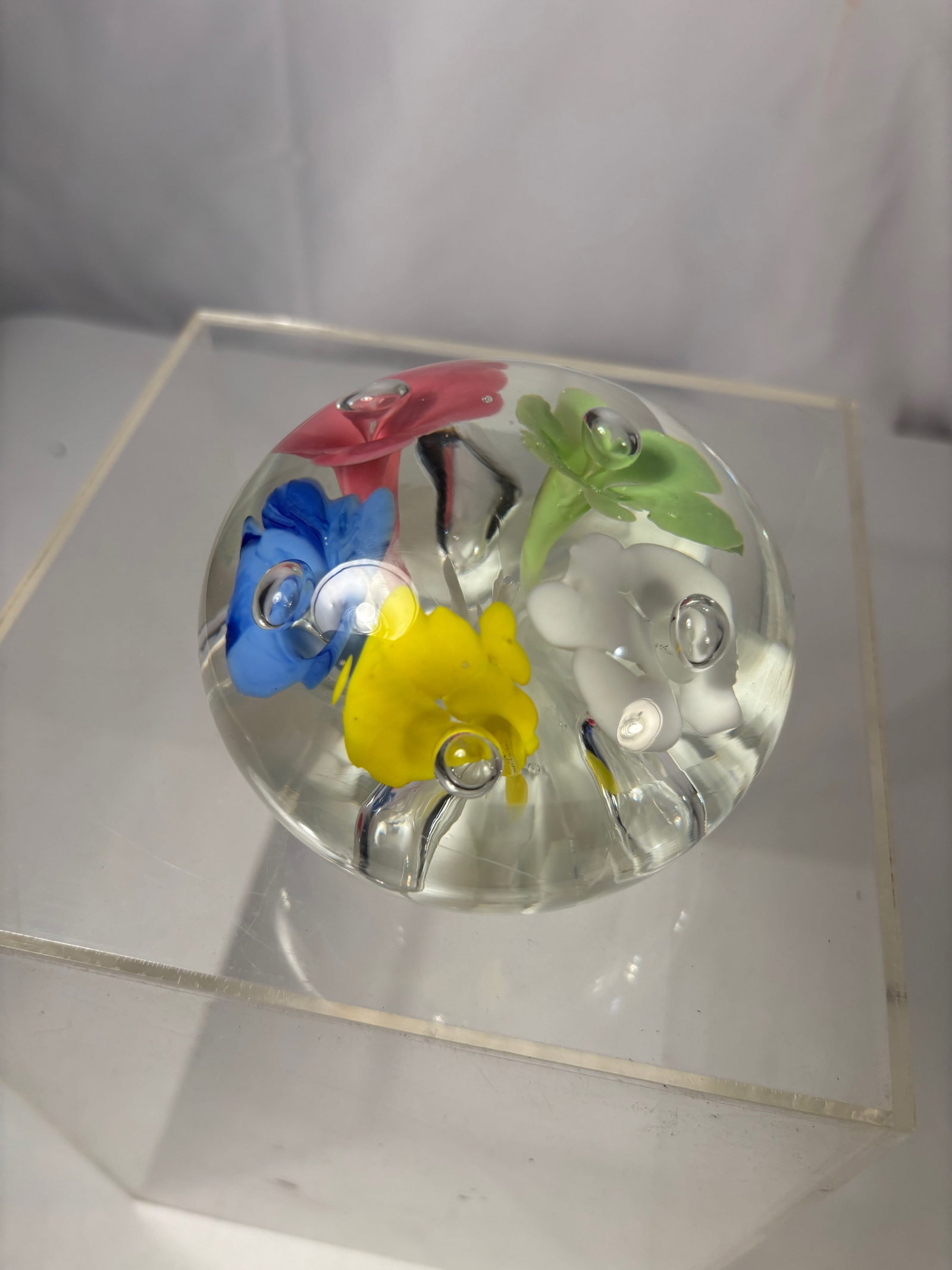 Art Glass Paperweight w/ Multicolor Floral Inclusions & Bubbles Signed St Joe Claire: Decorative art glass paperweight featuring a clear domed form with vibrant multicolor floral inclusions, including red, blue, yellow, green, and white blossoms. The flowers are suspended within the gl