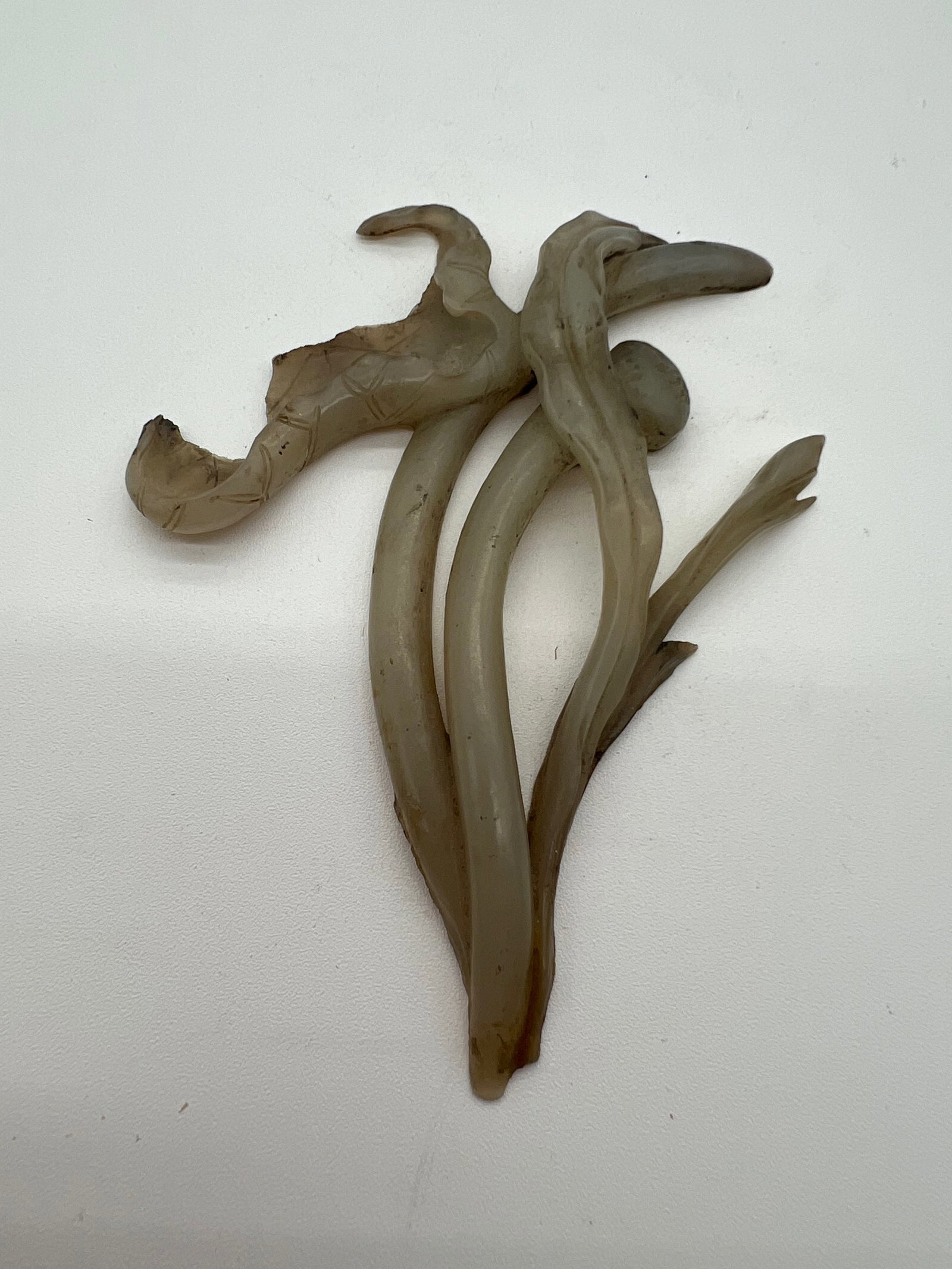 A Chinese hand carved celadon jade flower statue: Qing dynasty (1644-1912); The object in this image appears to be an abstract or naturalistic carving, possibly of a branch with vines or tendrils, which could indeed be made of celadon jade. Dimension