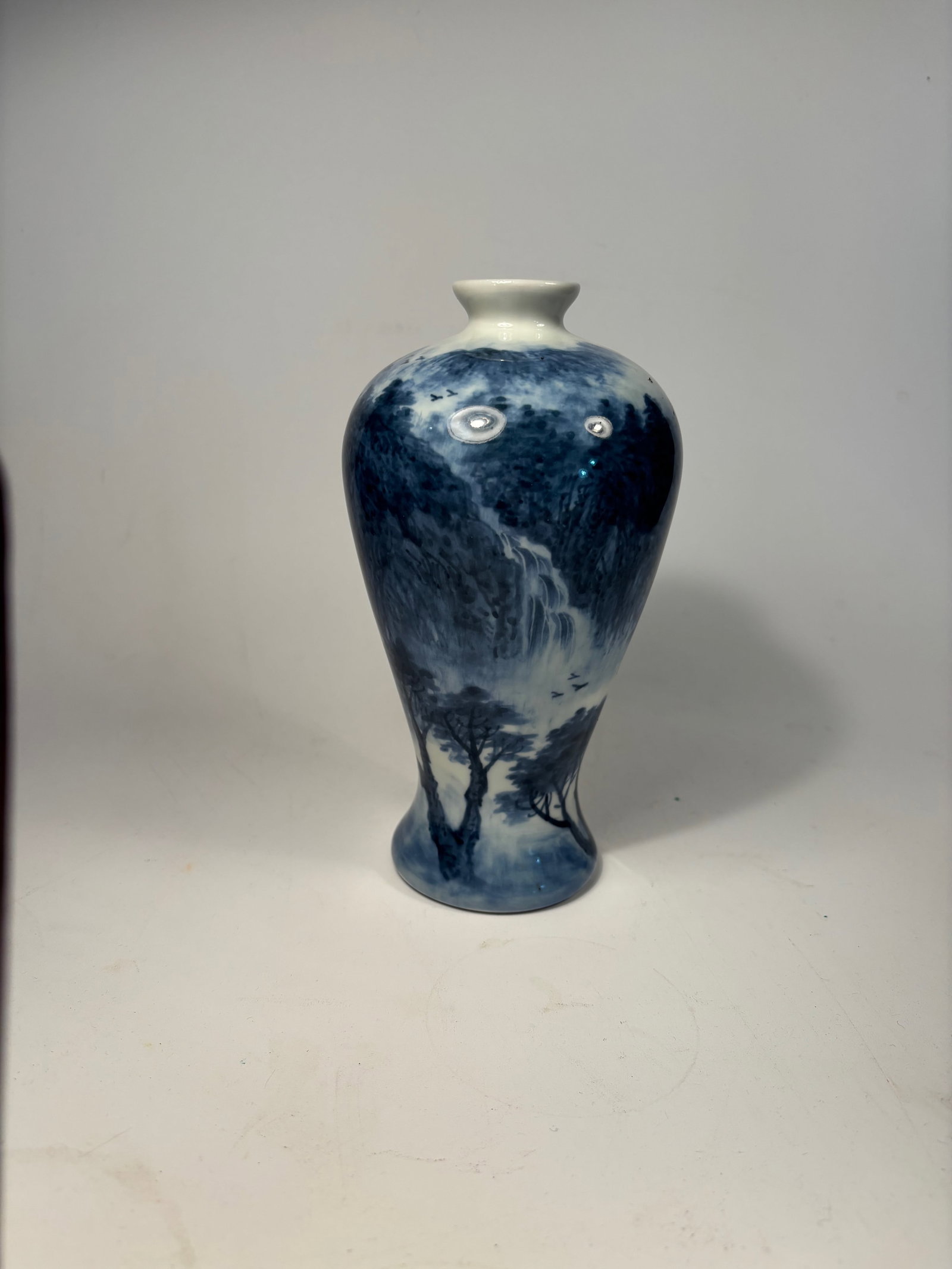 An Asian blue and white porcelain vase: 20th Century, The body features a finely painted mountainous landscape with a flowing spring and tree, accompanied by poetic calligraphy; Dimensions?Height: 8 inches.
