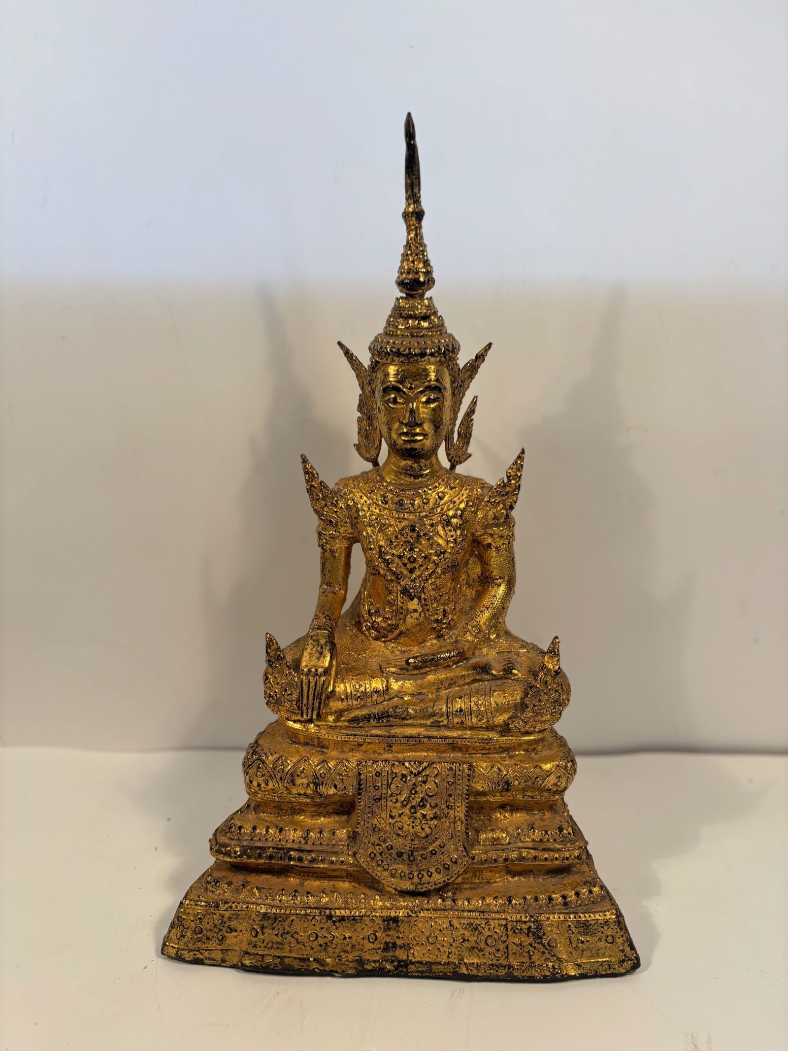 A Thai Gilt Bronze Buddha in Royal Attire, Rattanakosin Style: late 19th century, Royal Attire: the figure wears a highly ornate crown and jewelry, indicating a Buddha in royal costume (Phra Phuttha Chao Si Sawan style).Cast bronze, surface gilt with gold leaf.Th