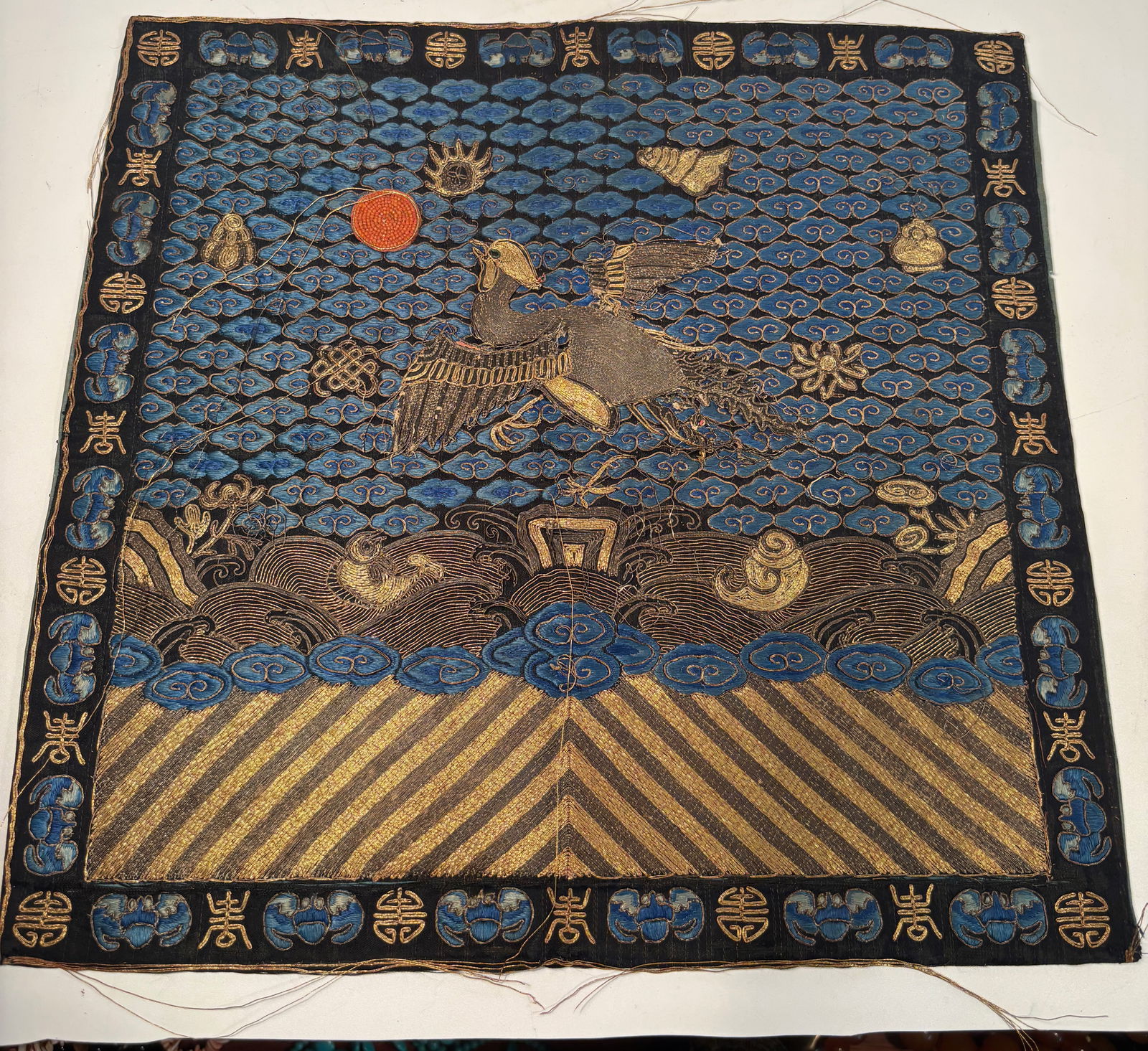 A Fine Qing Dynasty Embroidered First-Rank Civil Badge (Buzi) with Coral Bead Sun,: A finely embroidered civil rank badge (buzi) depicting a crane flying toward a coral-bead rising sun, signifying the first-rank civil official in the Qing court hierarchy. The crane is rendered in sil