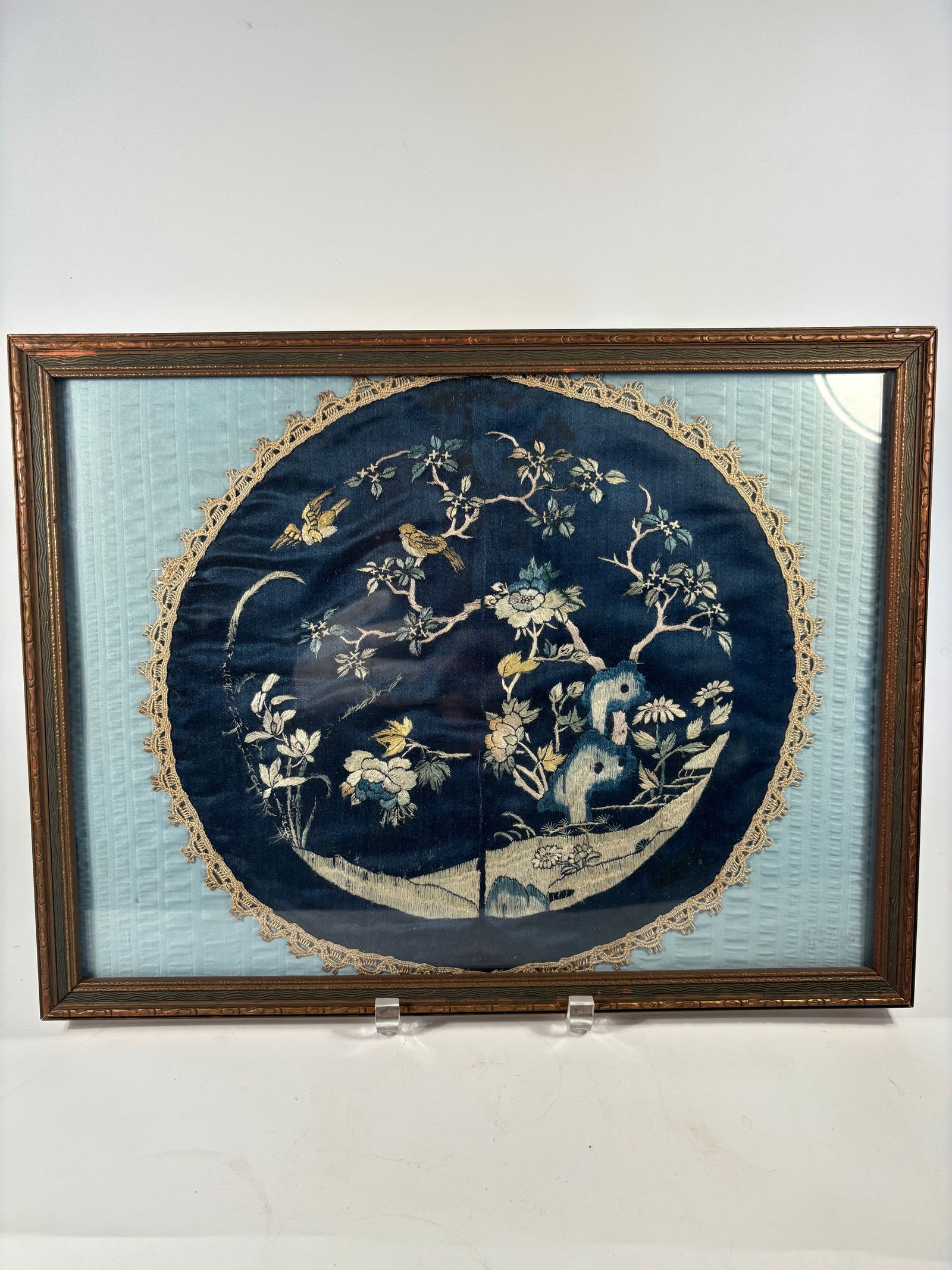 A Chinese Embroidered Silk Fan Leaf with Birds and Blossoms, Framed: Qing dynasty(1644-1912) ; A finely hand-embroidered silk fan leaf depicting an elegant garden scene with birds perched among flowering trees and rocks, set against a rich cobalt-blue silk ground. The