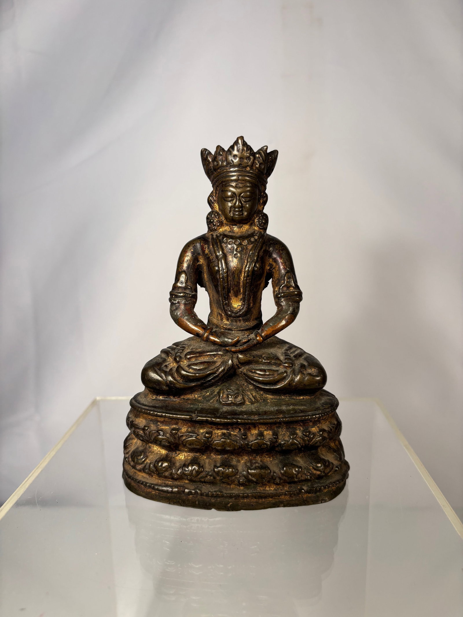 A Chinese Gilt Bronze Seated Guanyin Bodhisattva Figure: Qing Dynasty (1644-1912); A Chinese gilt bronze seated figure of Guanyin, the Bodhisattva of Compassion, shown in a meditative posture upon a tiered lotus base. The figure is finely cast with a serene