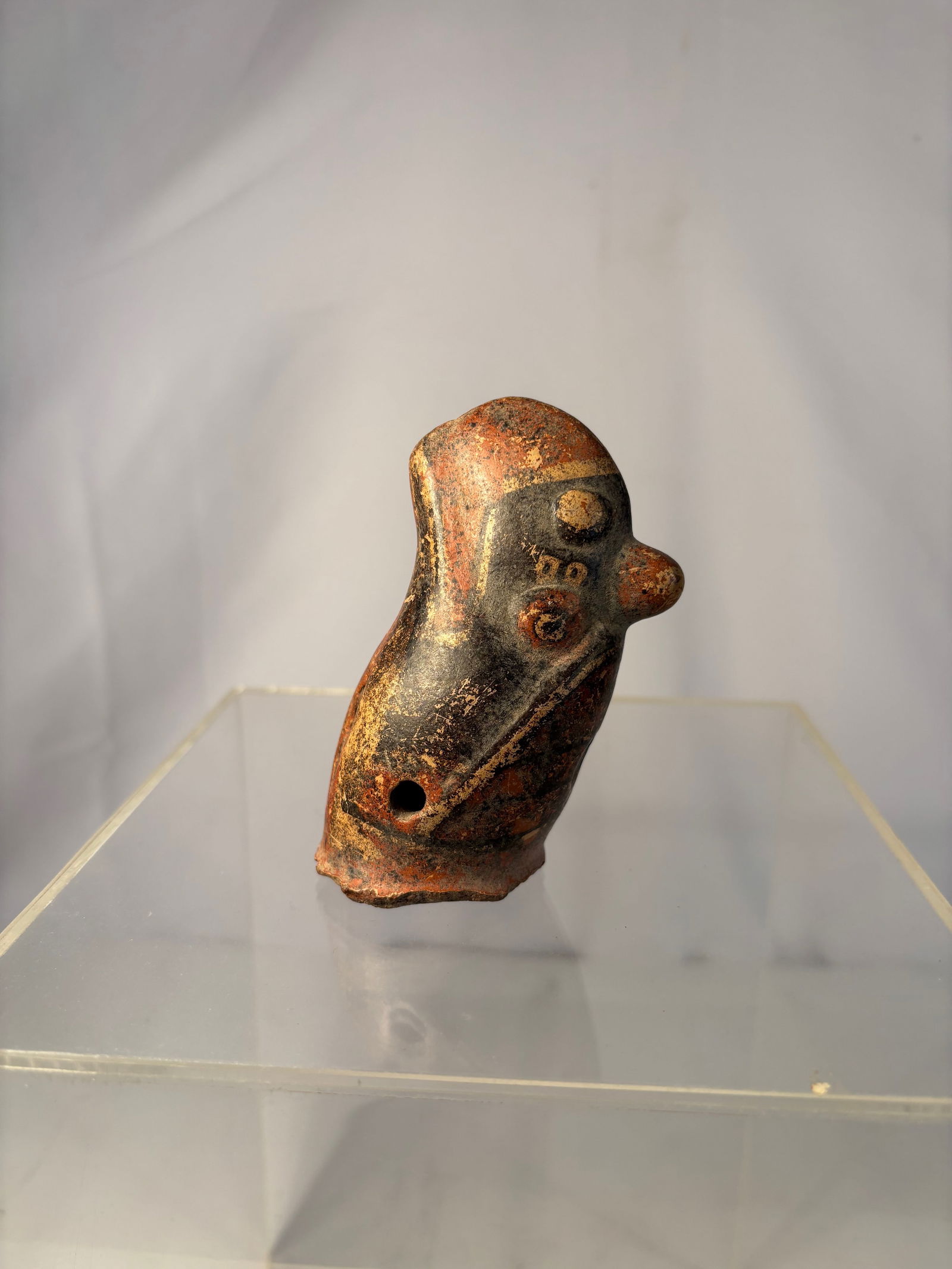 Pre-Columbian pottery whistle, also known as an ocarina. Costa Rican, specifically from the Diquis: Pre-Columbian (ca. 800–1525);The artifact is small, made of reddish-brown clay with a polished finish, and features black and red slip decoration. It has distinct features resembling a head with a p