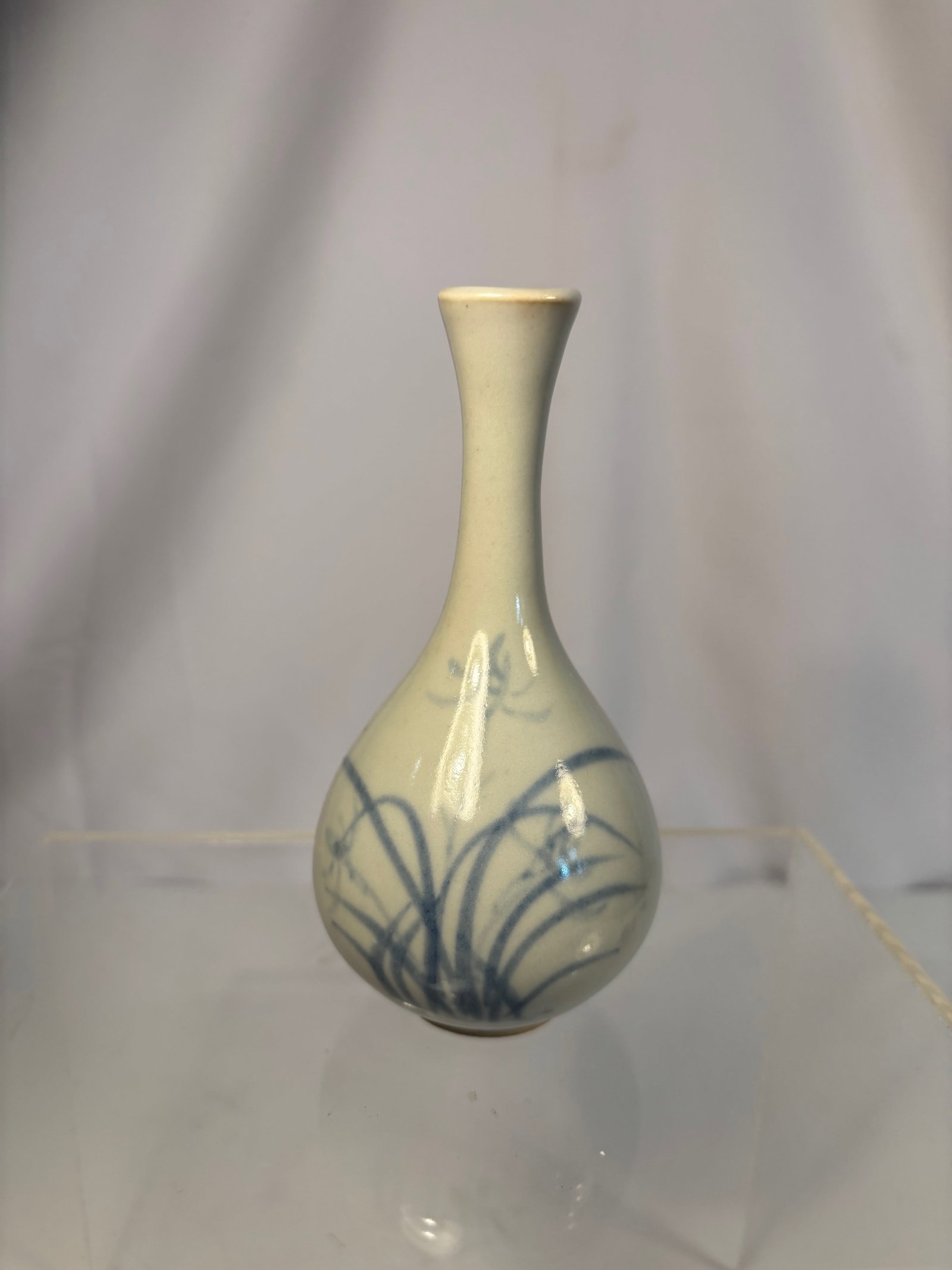 A Korean Blue and White Porcelain Vase with “Gojak?? (???) Mark, Early 20th Century: A fine Korean blue and white porcelain vase of elegant pear shape with a slender neck, the body delicately painted in flowing cobalt brushstrokes with orchid sprays and grasses—a motif deeply associ