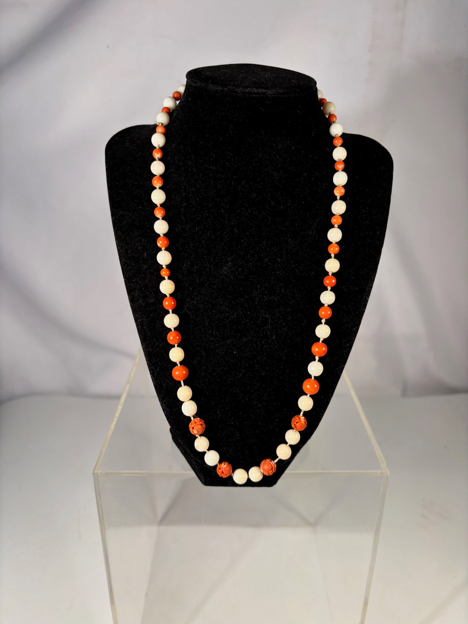 A White Coral and Red Coral Bead Necklace with Carved Coral Accents: Necklace composed of alternating white coral beads and red coral beads, accented with several larger carved coral beads featuring floral motifs. The necklace displays a pleasing contrast between the c