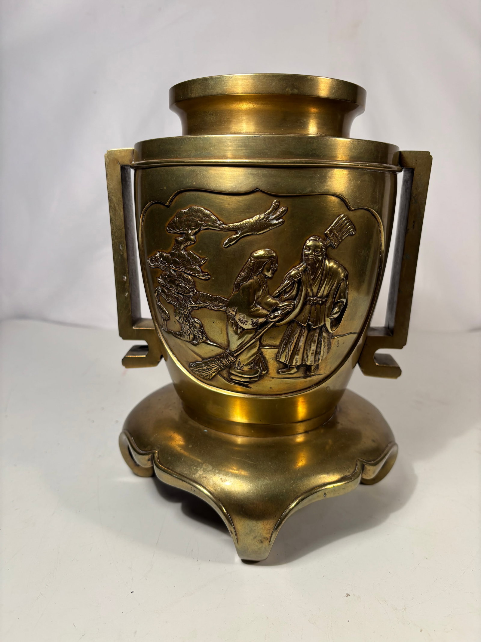 A Japanese Bronze Relief Vase with square seal mark: A fine Japanese bronze vase in the Meiji taste, cast with figural relief scenes including robed elders, attendants, pine trees, and cranes in a traditional longevity landscape. The vessel features str