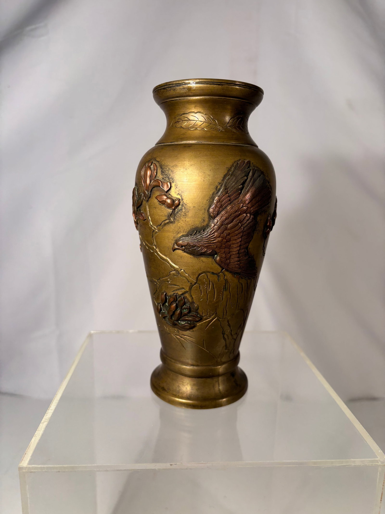 A Japanese mixed-metal bronze vase, Meiji Period: A fine Japanese bronze vase in the Meiji taste, decorated in mixed-metal relief with a dramatic hawk in flight among blossoming magnolia branches, smaller birds, and incised bamboo leaves near the bas