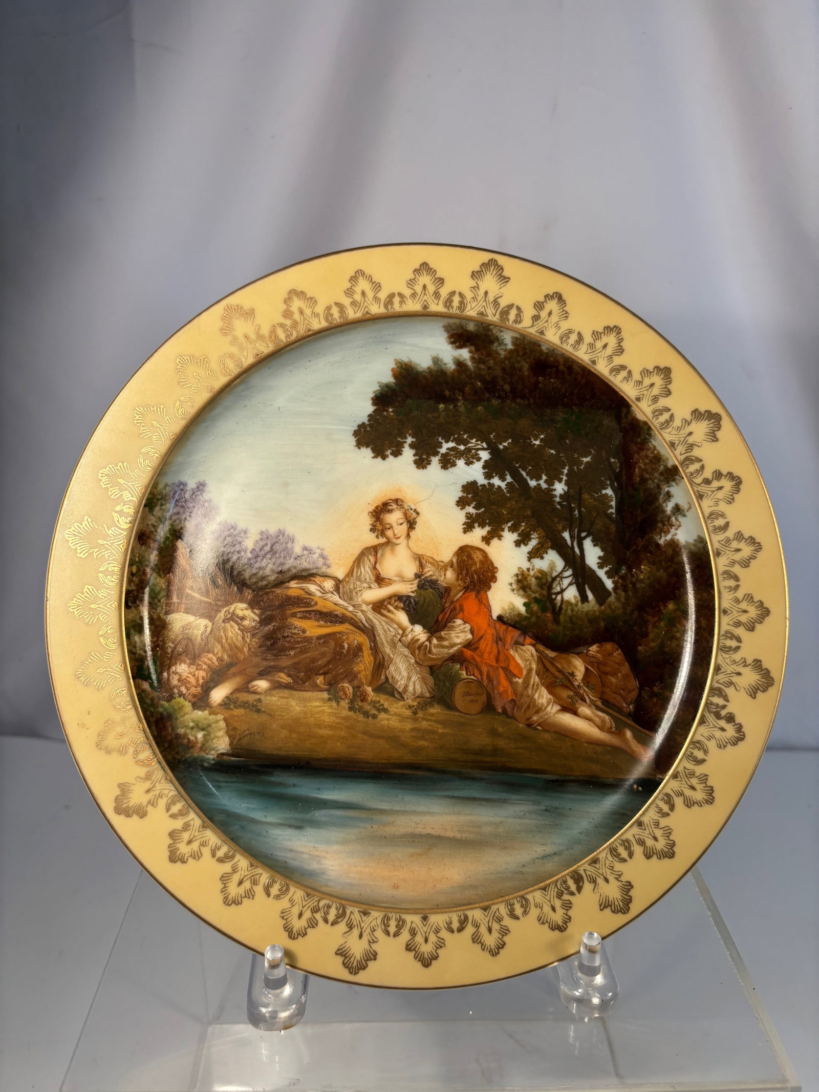 A Hand-Painted Porcelain Cabinet Plate, “Pastoral Lovers,?? in the Style of François Boucher,: A beautiful hand-painted porcelain cabinet plate depicting a romantic pastoral scene of a young shepherd and shepherdess resting beside a stream under a tree, inspired by the works of François Bouche
