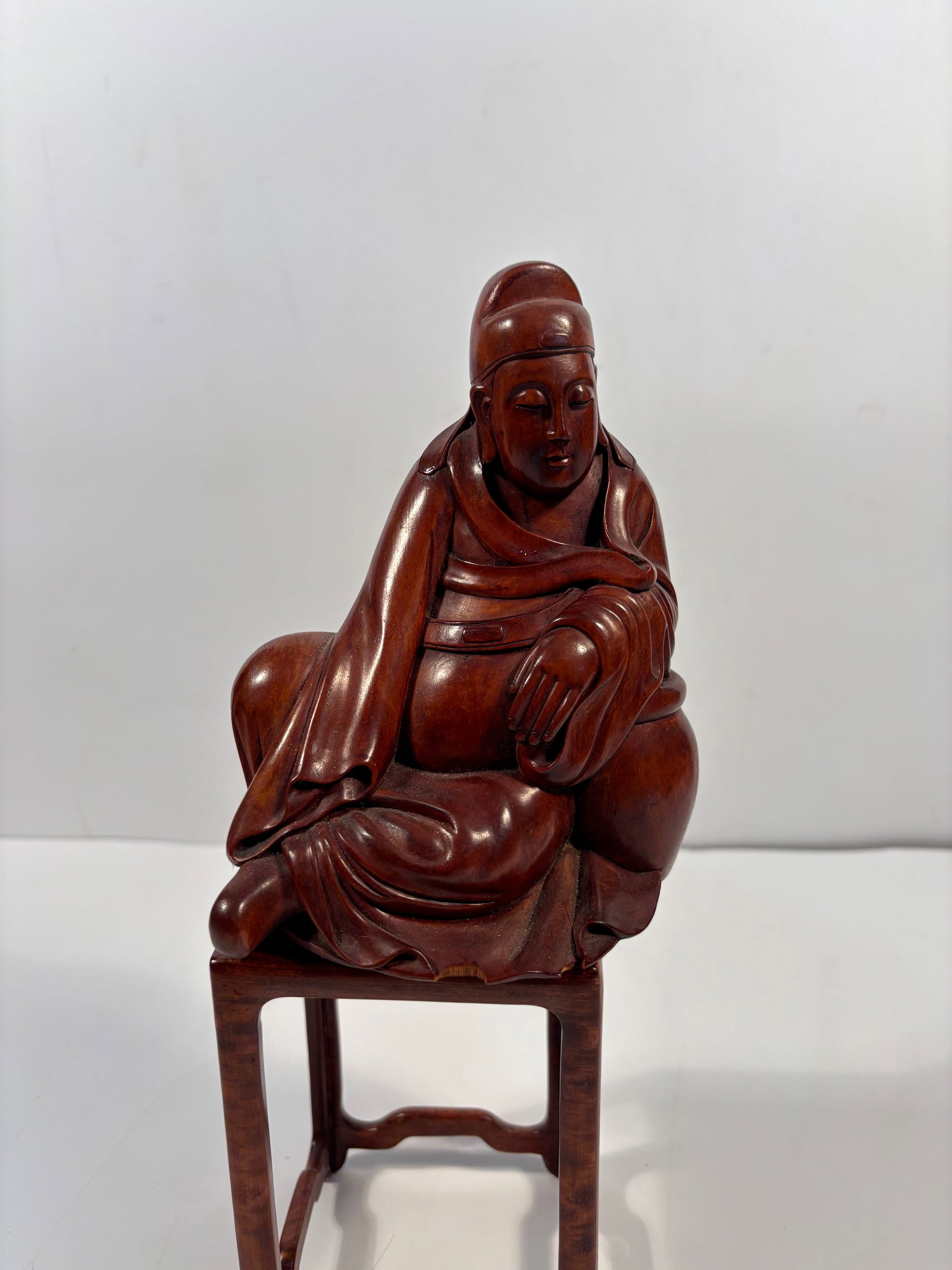 A Chinese hand carved boxwood figurine statue: Qing Dynasty (1644-1912),The figure is seated in a relaxed posture, with one arm resting across the body. The facial expression is serene, the carving of the robes is fluid, and the overall form is