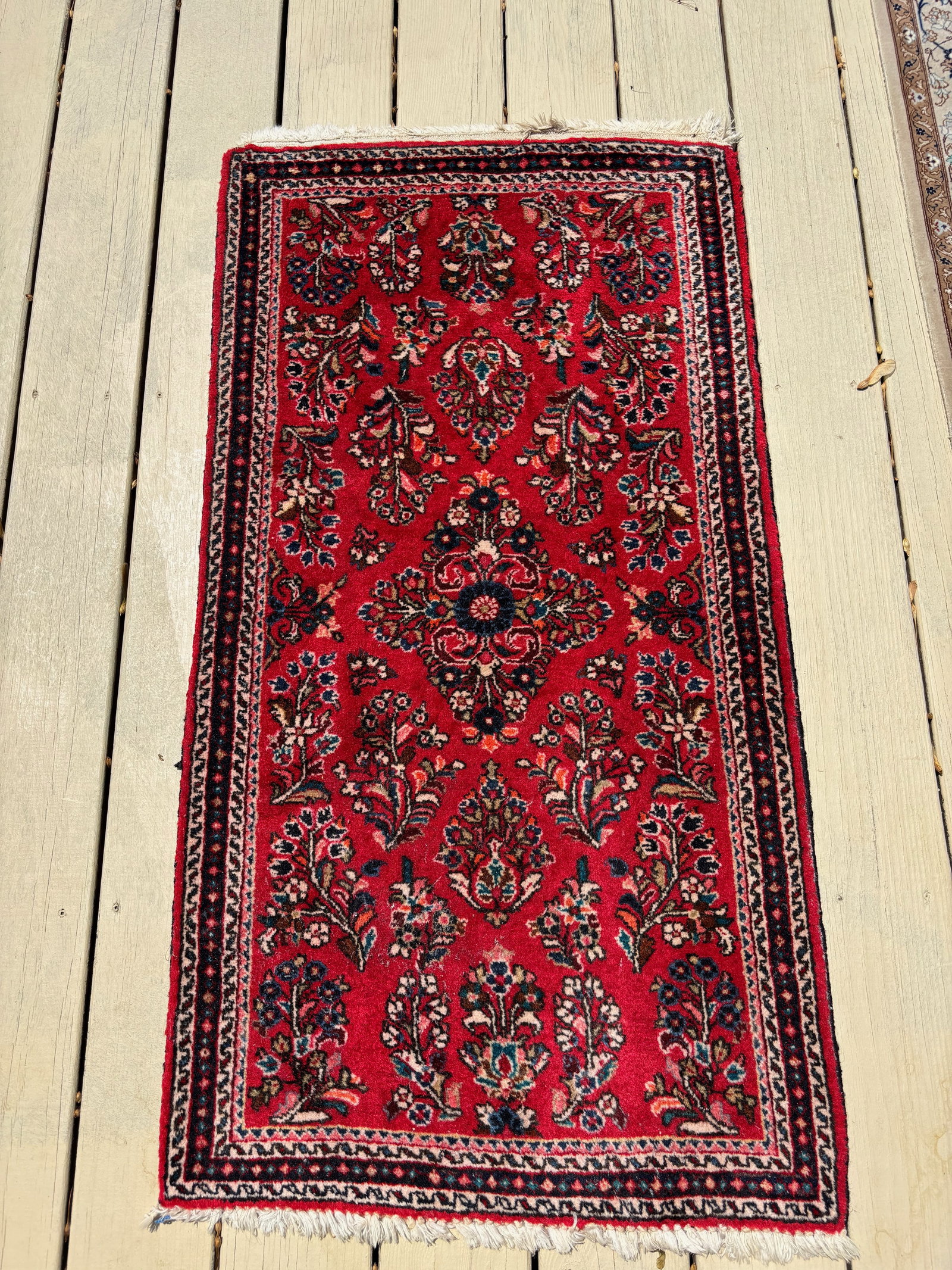 A Persian Sarouk (Sarough) 100% wool rug: Probably Early to mid-20th century;A hand-knotted Persian Sarouk rug, woven in central Iran, featuring a rich red field adorned with sprays of floral motifs arranged in a symmetrical allover pattern.