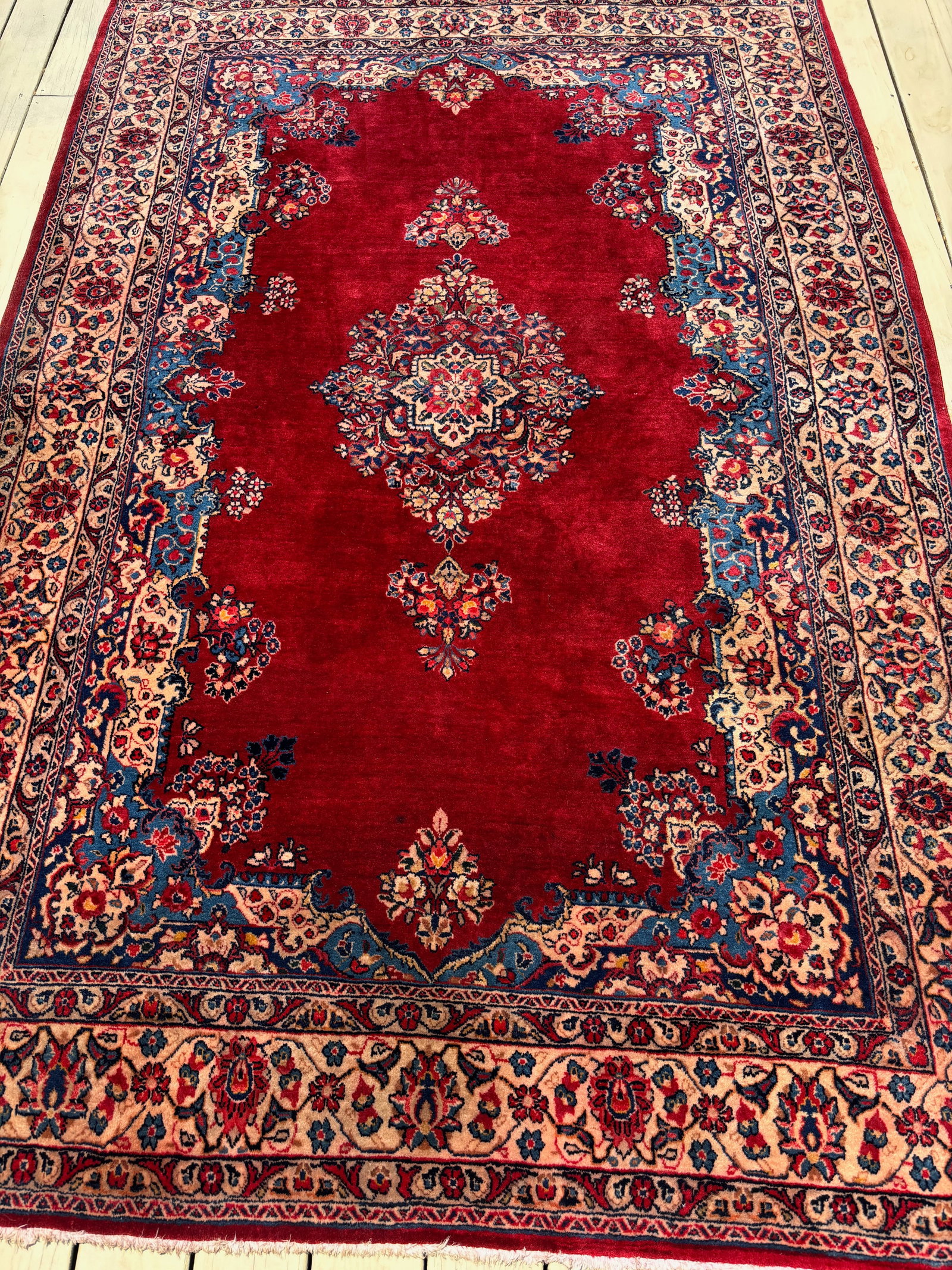 A Persian kashan 100% wool Rug: Probably Circa 1930; A finely hand-knotted Persian Kashan rug from the early 20th century, originating in Central Iran. This elegant piece features a rich red field centered by a symmetrical floral me