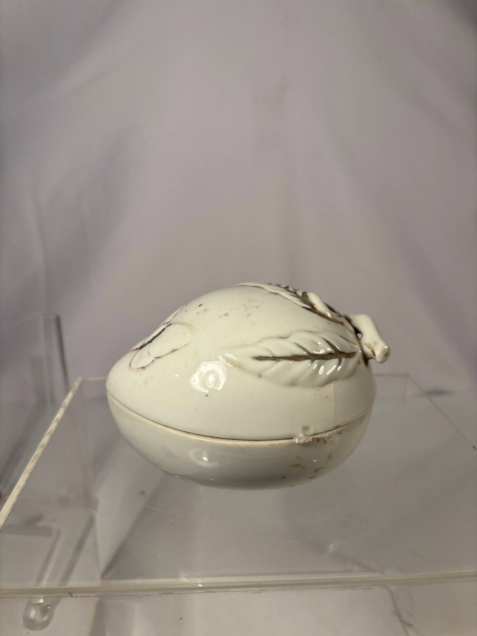 A Chinese White-Glazed Peach-Form Covered Box: Qing dynasty(1644-1912) ; A Chinese white-glazed porcelain covered box modeled in the form of a peach, the lid applied with molded leaves and a short stem, all highlighted with light brown accents.