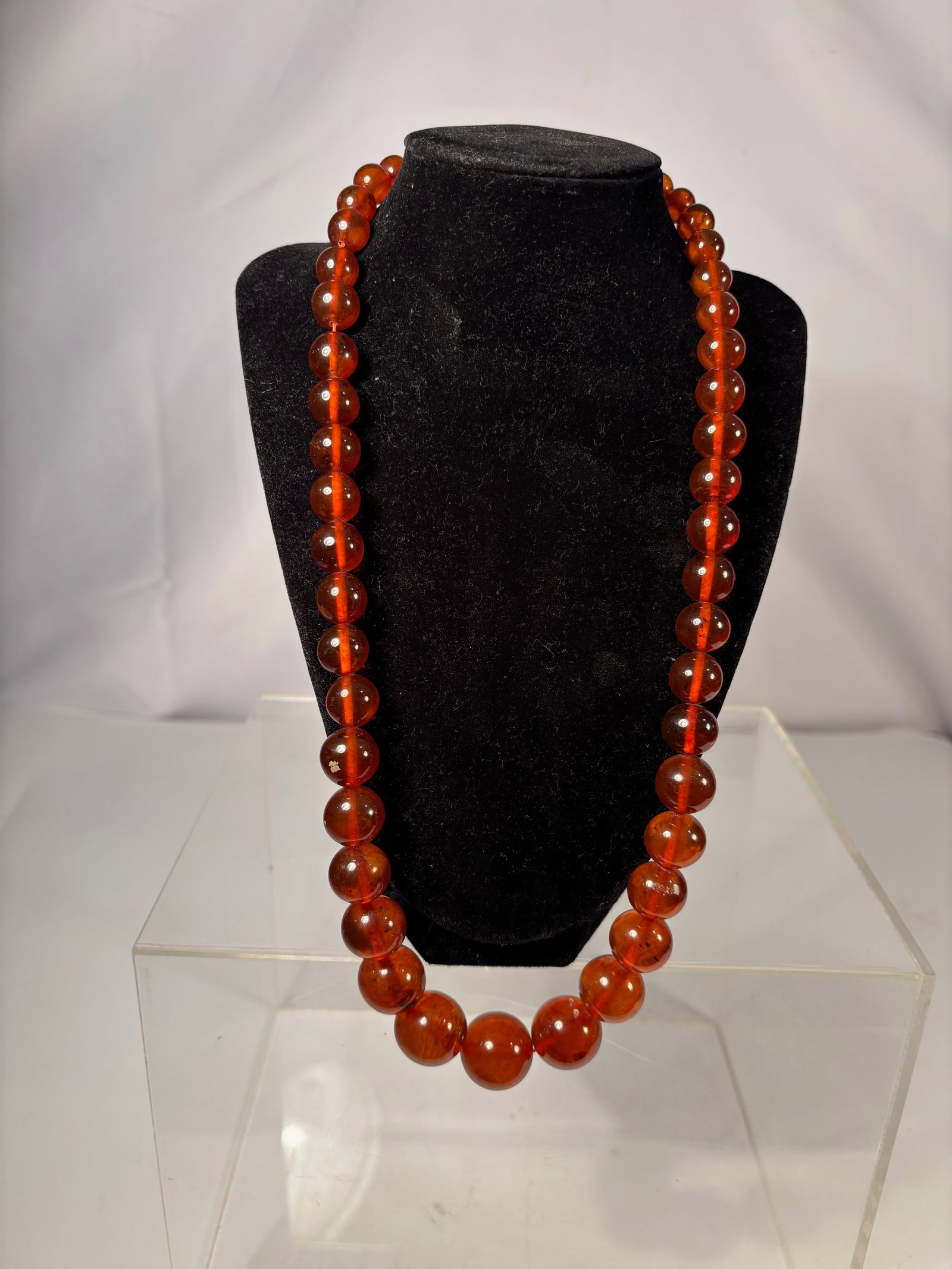 An Amber Translucent Bead Necklace: This necklace features smoothly polished translucent amberbeads, displaying warm reddish-brown tones and internal clarity variations. The beads are graduated in size and evenly strung, forming a class