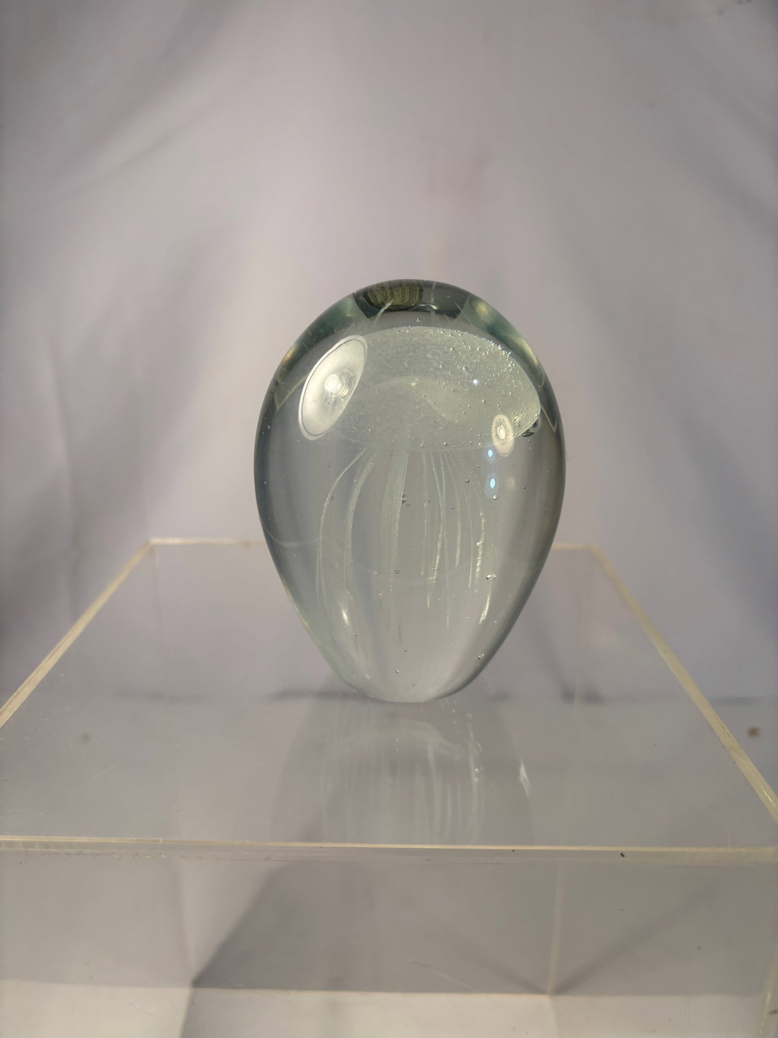 A Dynasty Gallery Jellyfish Art Glass Paperweight: A contemporary art glass paperweight by Dynasty Gallery, featuring a clear dome form with an internal sculpted white jellyfish floating above a soft aqua-green base. Nicely detailed tentacles suspende